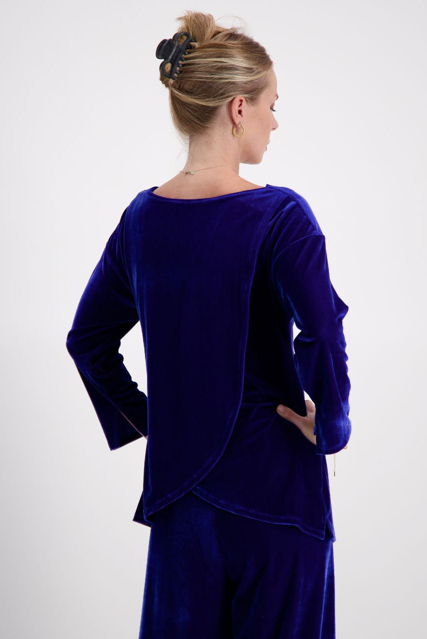 Emma Boat Neck Leaf Back Top shown from behind in luxurious cobalt blue velvet, featuring distinctive overlapping leaf design on back, three-quarter length sleeves with split cuffs, against light background. Elegant upswept hairstyle completes the sophisticated silhouette.