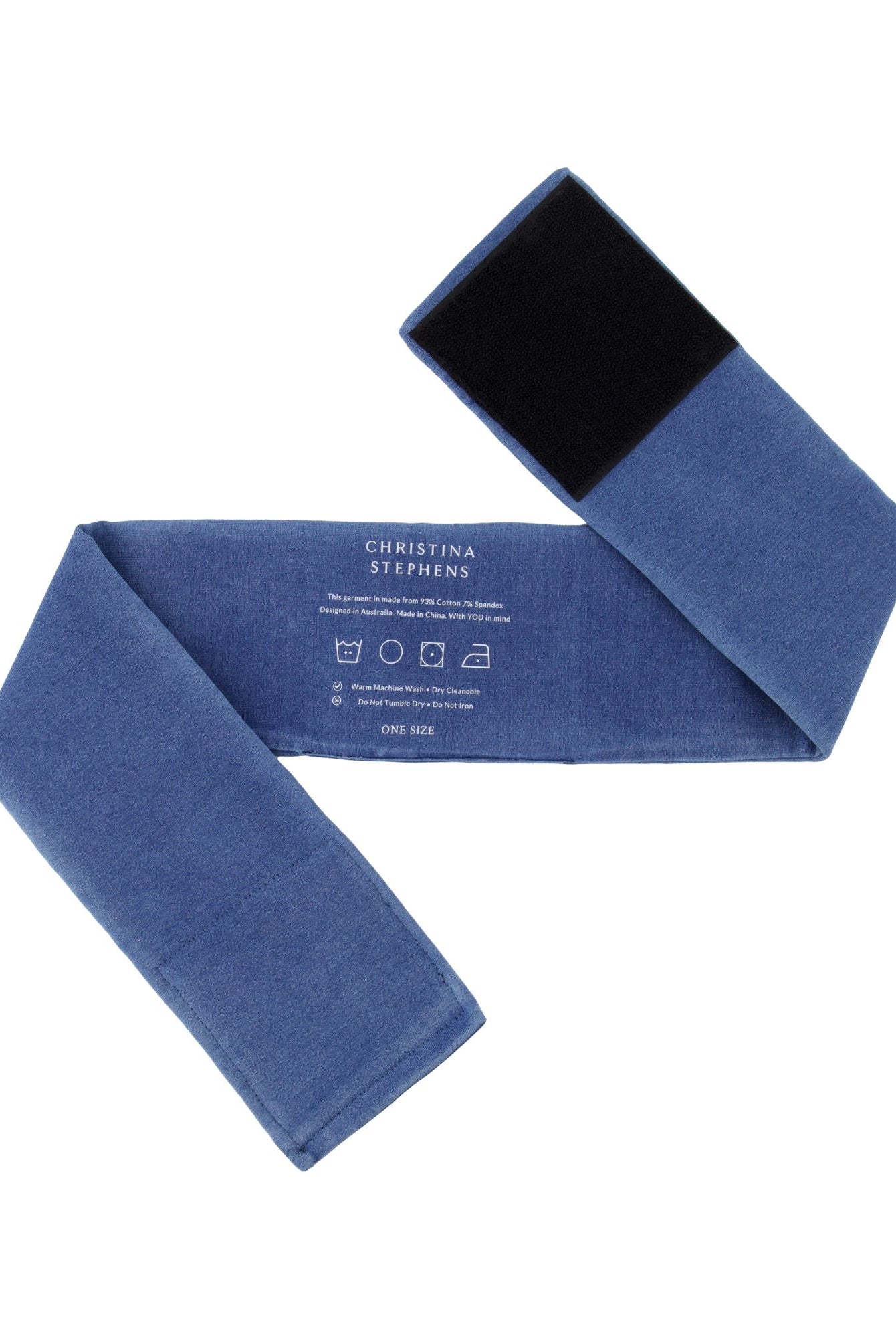 Wheelchair Leg Strap in denim blue with black velcro fastener, featuring care instructions printed on soft fabric. Product shown flat and unfolded displaying full length and width of the adjustable support strap.
