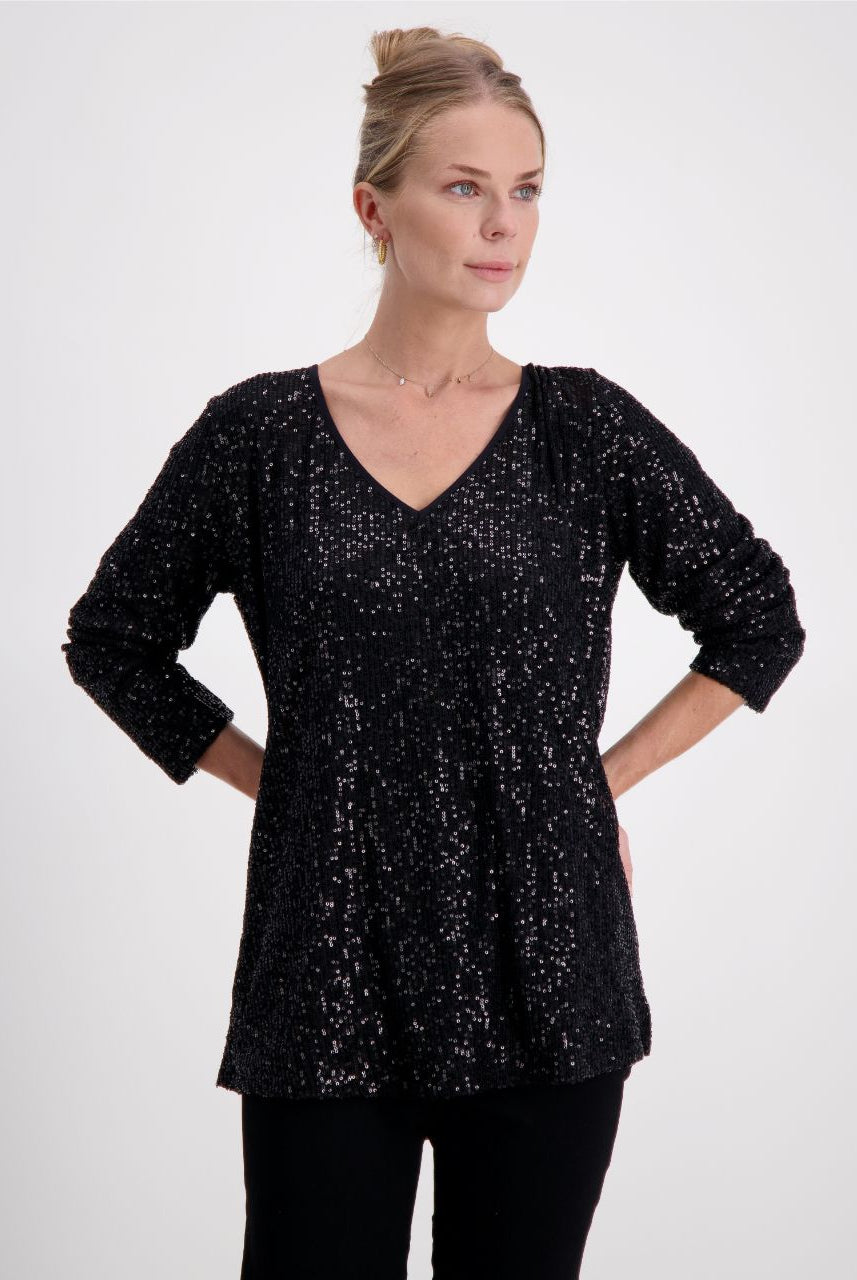 Tara V Neck Leaf Back Top in shimmering black metallic glitter fabric with long sleeves. Featuring a flattering V neckline, relaxed fit, and signature leaf pattern on the back. Perfect evening wear top with stretch sequin detail against light studio background.