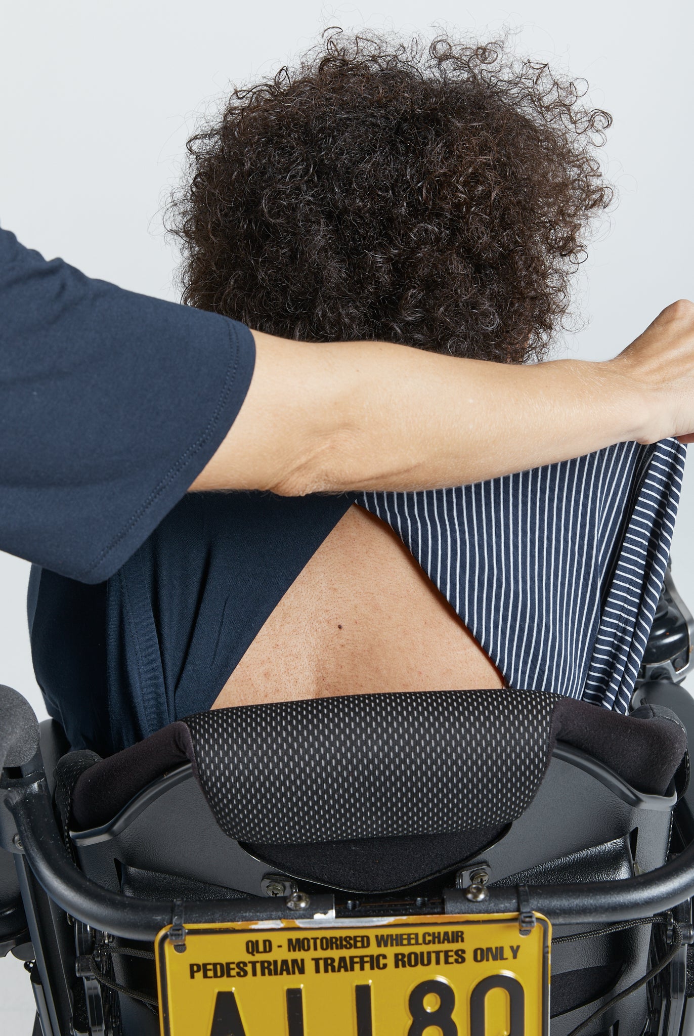 Cowl Neck Leaf Back Top shown from behind, displaying the unique back split design. A sleek navy blue fabric drapes elegantly, highlighting the garment's adaptive features and comfort-focused design against a neutral background.
