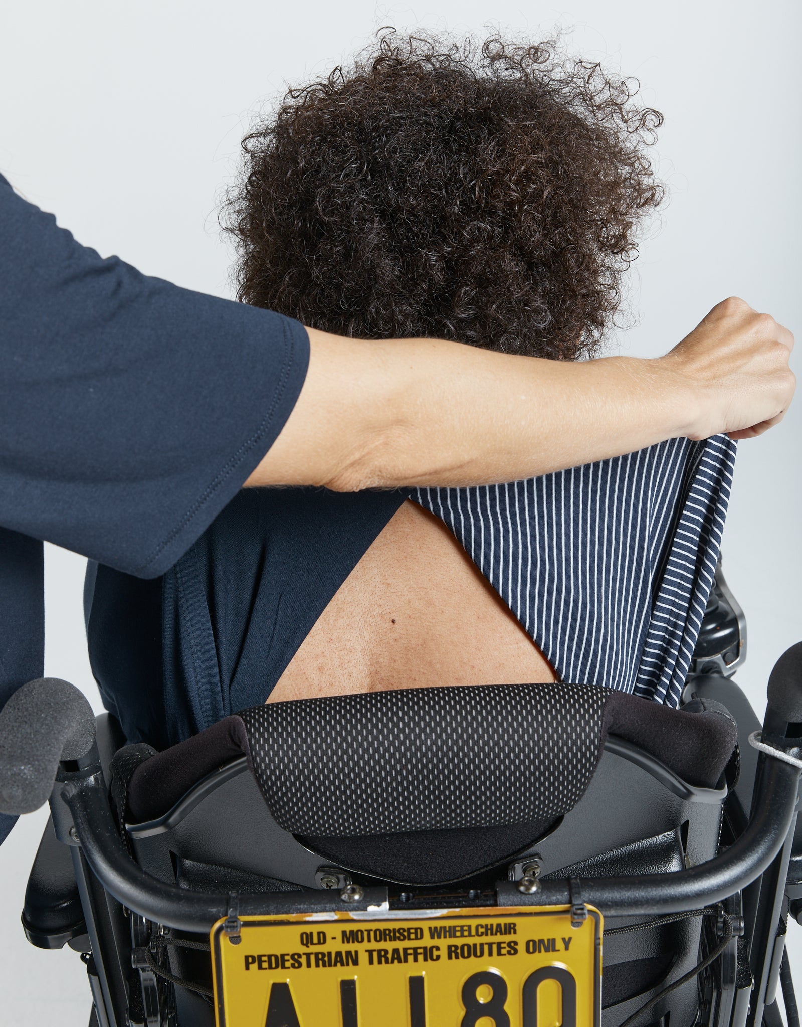Cowl Neck Leaf Back Top shown from behind, displaying the unique back split design. A sleek navy blue fabric drapes elegantly, highlighting the garment's adaptive features and comfort-focused design against a neutral background.