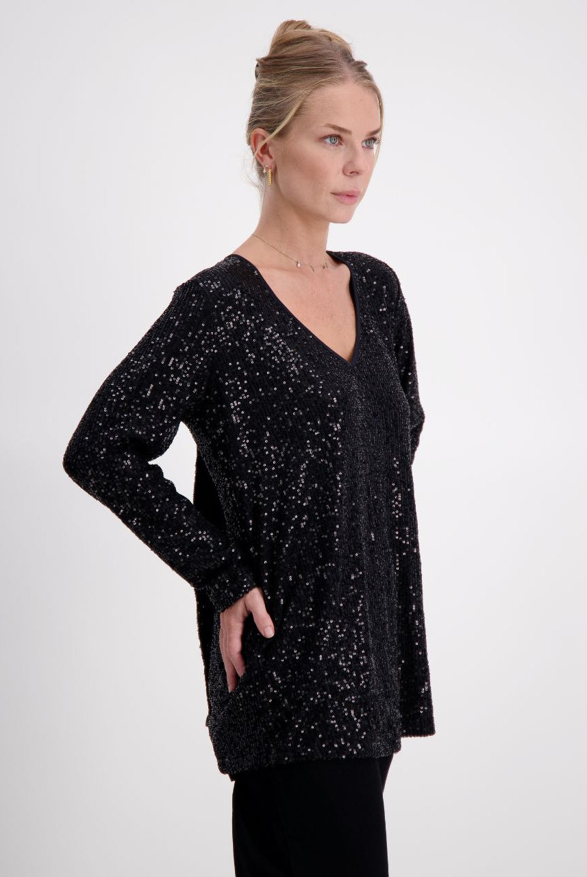 Tara V Neck Leaf Back Top in shimmering black metallic glitter fabric featuring a plunging V-neckline and full-length sleeves. The elegant design showcases a signature leaf pattern on the back, perfect for evening wear.