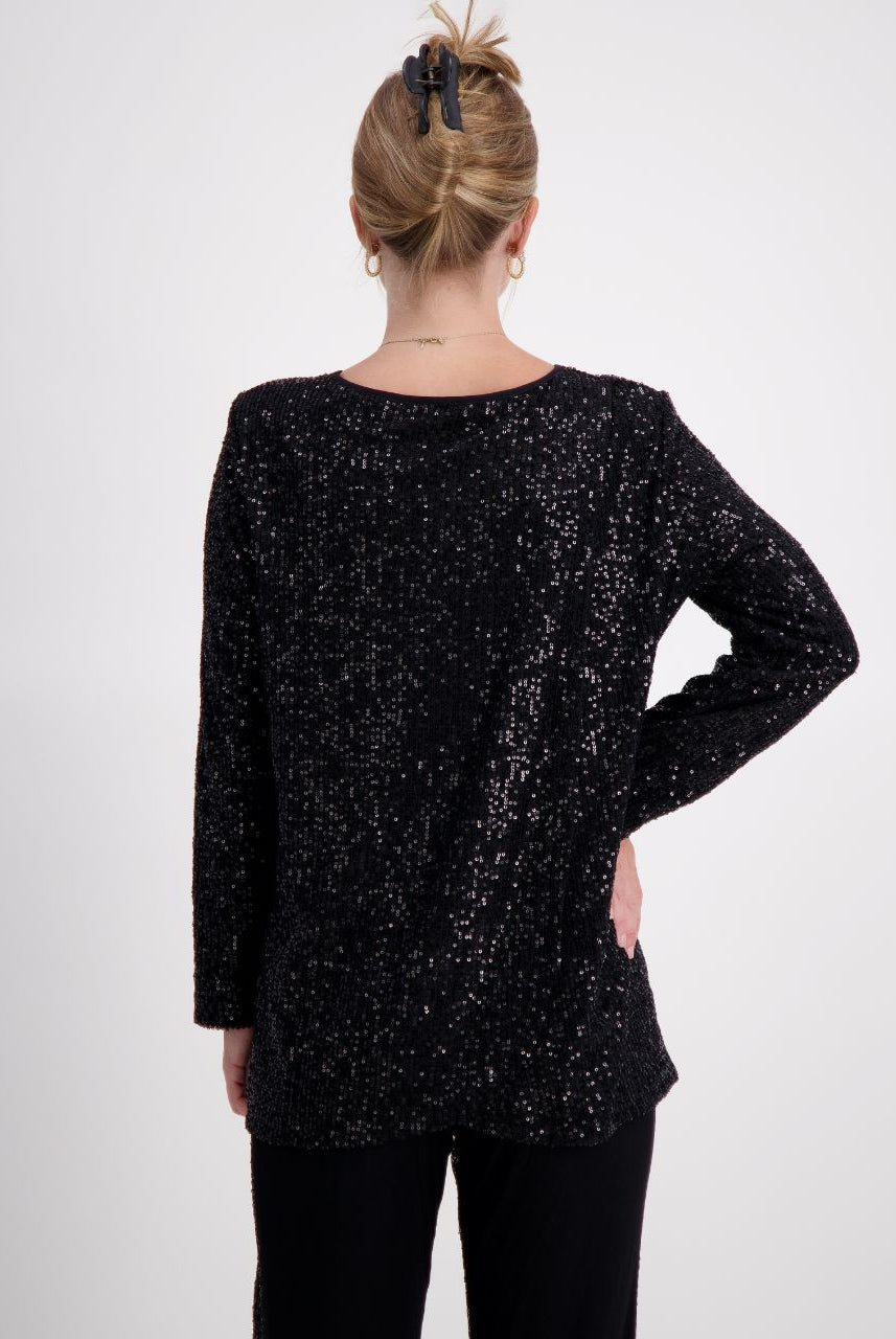 Tara V Neck Leaf Back Top shown from behind, featuring a shimmering black metallic glitter fabric with full-length sleeves. The distinctive leaf-pattern back design is elegantly displayed on a model wearing a casual updo hairstyle against a light gray background.