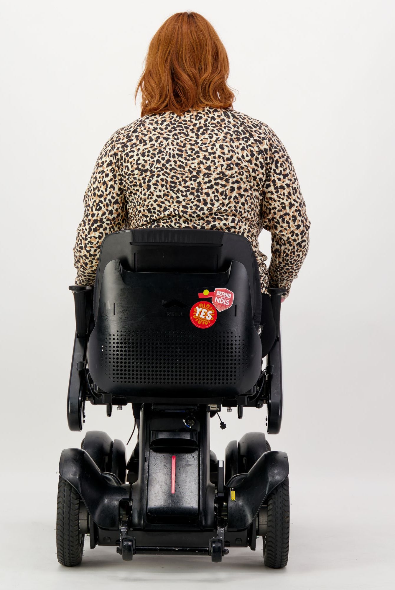 Back view of the Maggie Thermal Top in leopard print pattern, shown on a person seated in a mobility device, demonstrating the adaptive design and comfortable fit for wheelchair users