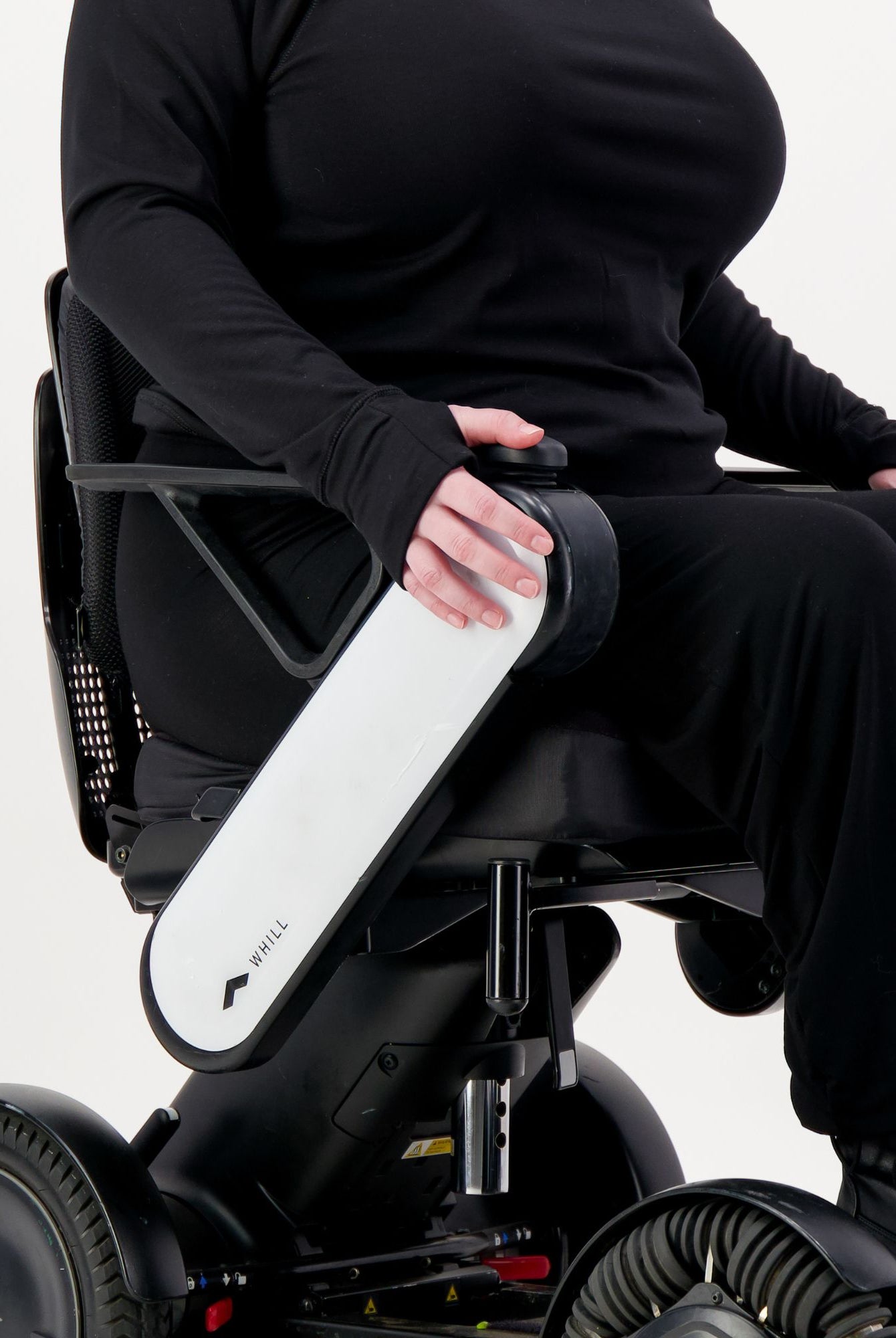 Maggie Thermal Top shown on a person seated in a power wheelchair, wearing all black attire. The close-up view highlights the top's comfortable fit and long sleeves, demonstrating its adaptive design for wheelchair users.