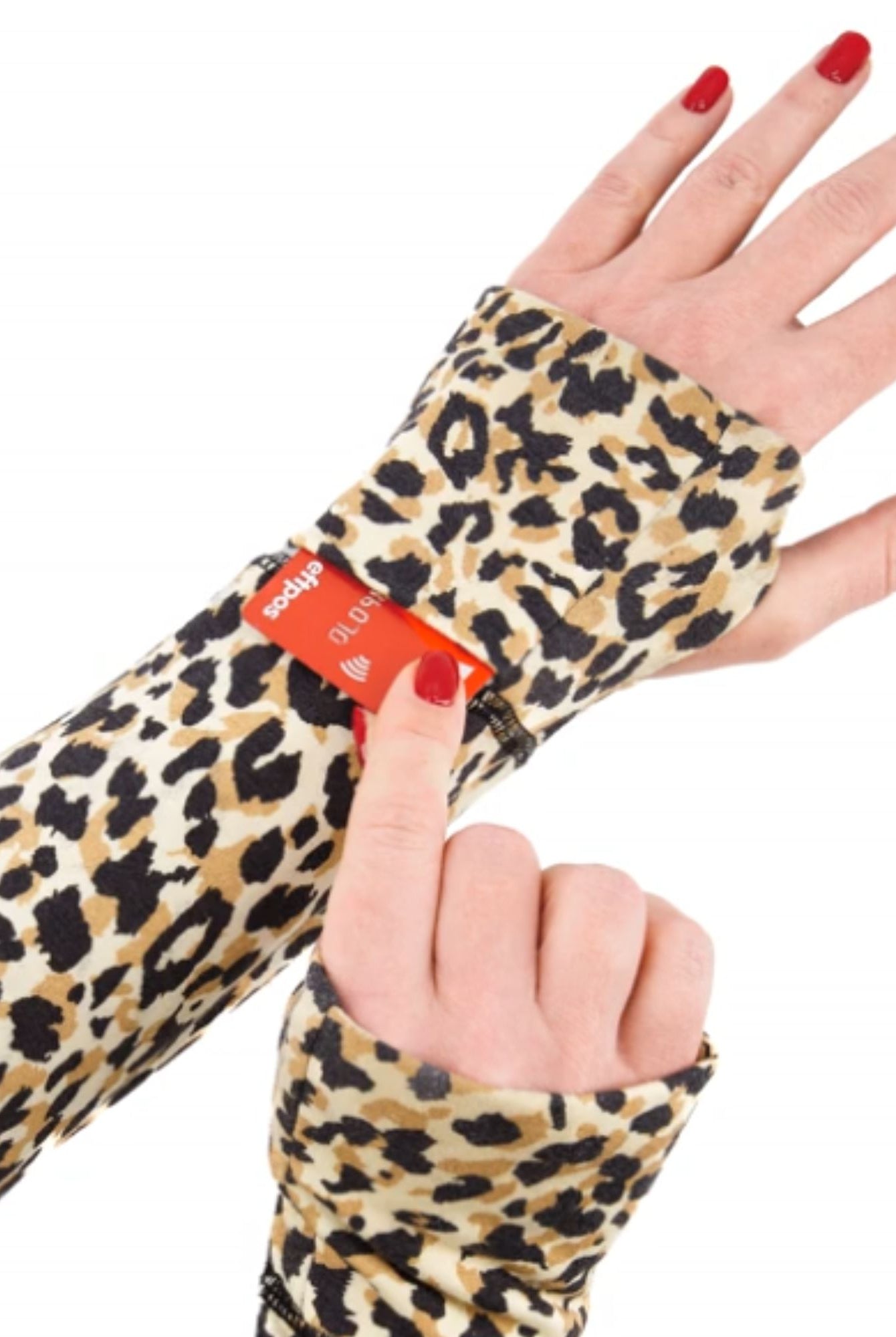 Maggie Thermal Top sleeve detail showing leopard print pattern with an adjustable red strap feature, demonstrated on a hand wearing red nail polish. The thermal material features classic tan and black spots on a cream background.