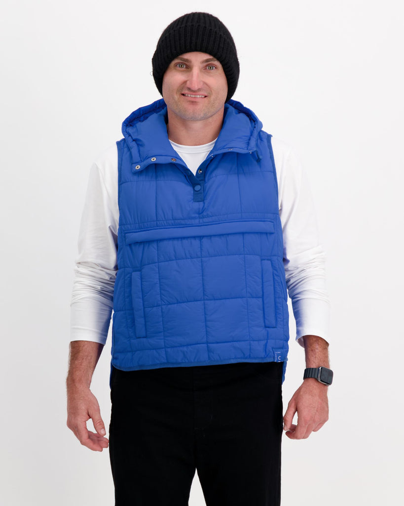 Standing male wearing a cobolt blue puffer vest over a white t-shirt and black pants. Christina Stephens Adaptive Clothing Australia.