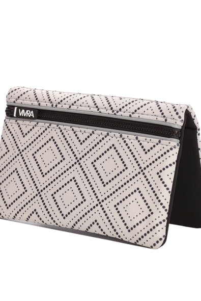 The VIVRA ‘Vivid’ waist bag in a black and white geometric pattern reminiscent of the Art Deco style, with a black zipper and a brand tag that says, ‘Vivra’, standing upright against a white background.