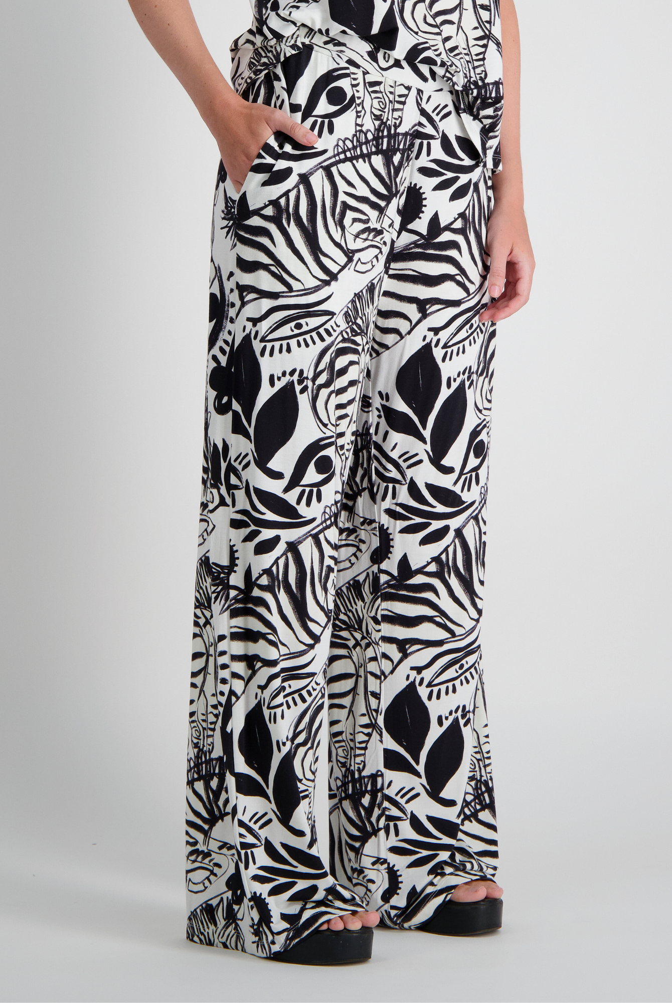 Jessie Wide Leg Pant showcasing a bold black and white abstract botanical and zebra print pattern on flowing wide-leg silhouette. Features side pockets and relaxed fit, made from bamboo and linen blend fabric for adaptive comfort.