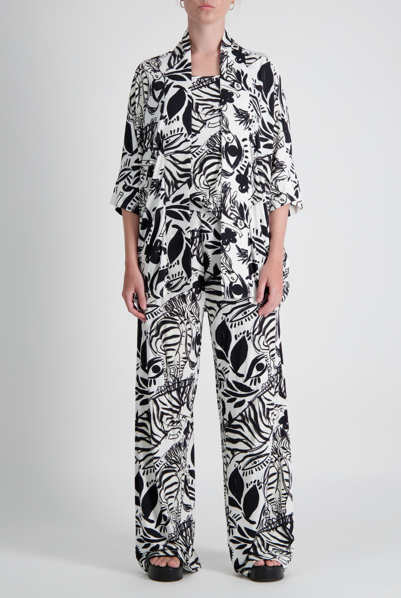 Jessie Wide Leg Pant shown in striking black and white abstract floral print pattern. Model wearing matching top with three-quarter sleeves. Wide-leg silhouette features comfortable, flowing design against light studio background.