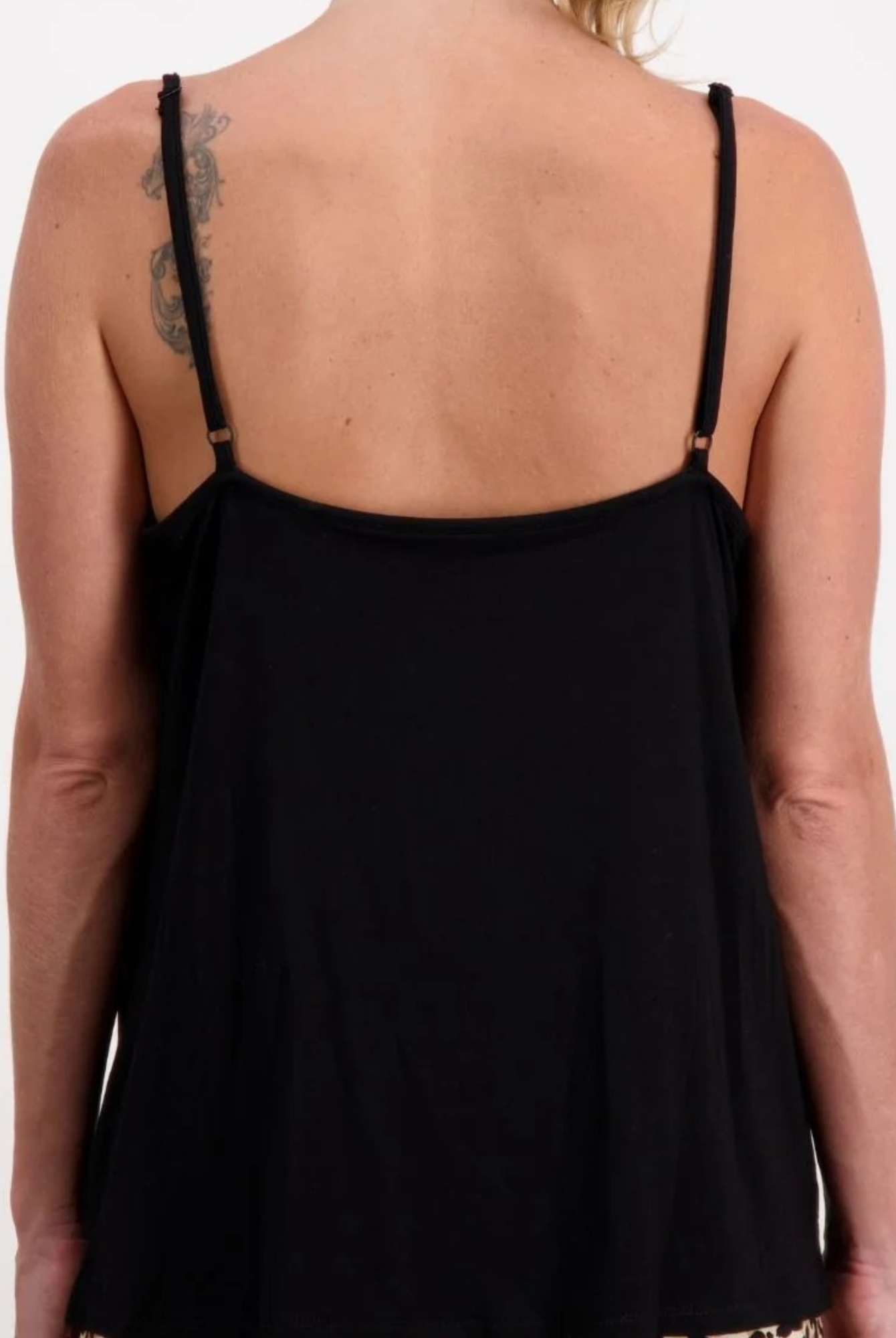 Back view of the Christine Adaptive Camisole in classic black, showing delicate adjustable straps and a flowing silhouette that drapes elegantly across the shoulders. The luxe layering essential features a clean-lined design with subtle details against fair skin.