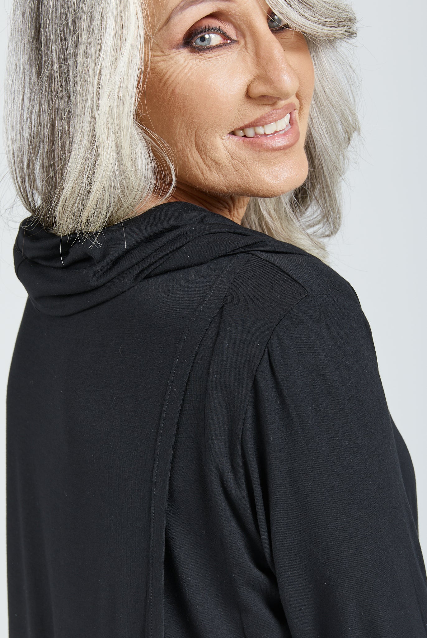 Elegant black Cowl Neck Leaf Back Top showcased in a side profile view, featuring soft draping around the neckline and comfortable 3/4 length sleeves. Made from luxurious bamboo fabric with a stylish back split detail.