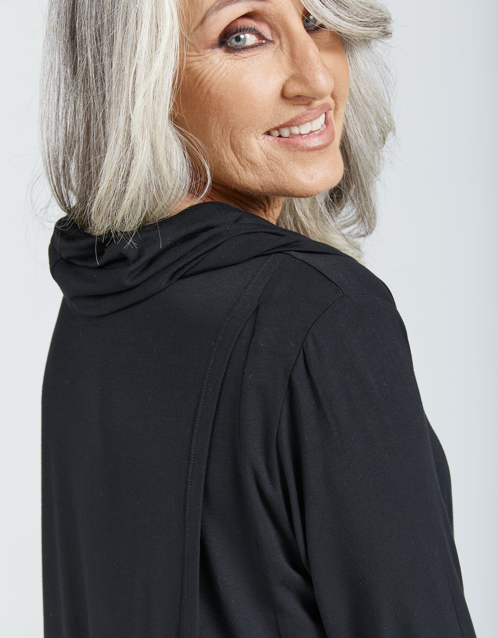 Elegant black Cowl Neck Leaf Back Top showcased in a side profile view, featuring soft draping around the neckline and comfortable 3/4 length sleeves. Made from luxurious bamboo fabric with a stylish back split detail.