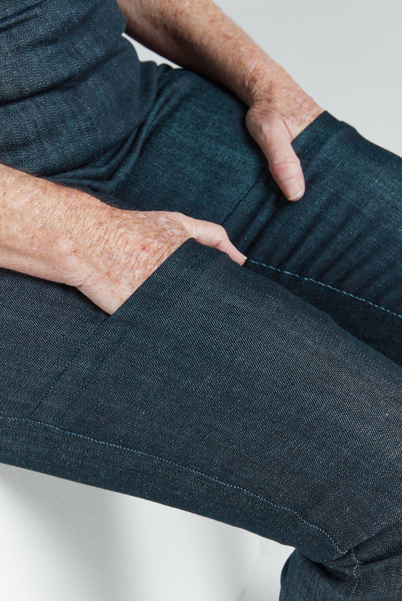 Close-up of hands in pockets wearing Women's Seated Stretch Pant - Indigo dark blue soft elastic trousers.