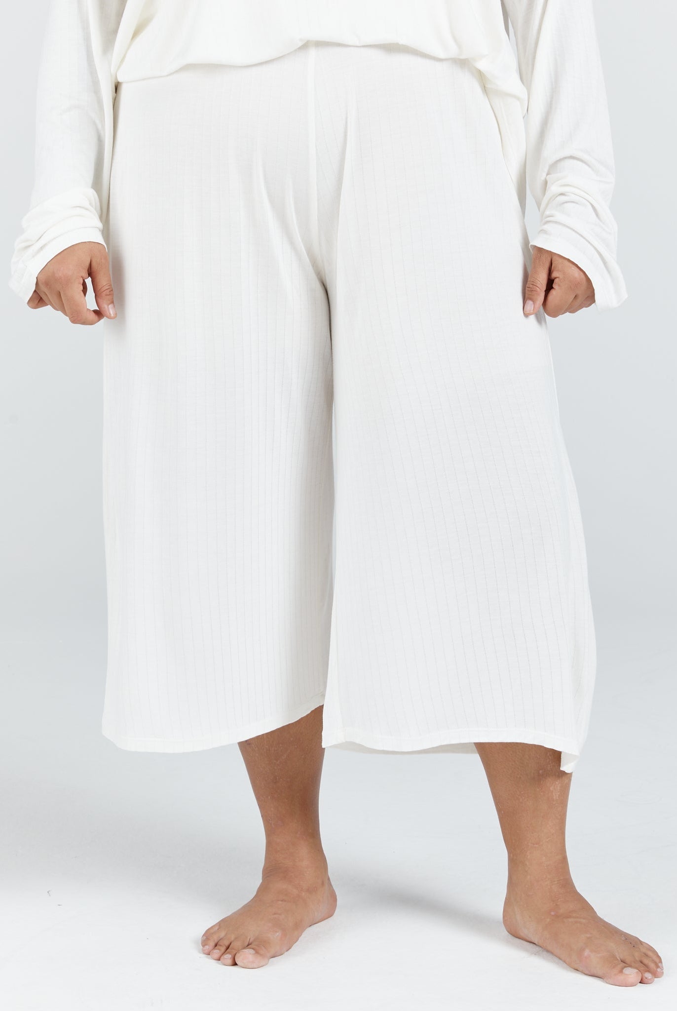 Essensual PJ Pant in pure white, featuring a comfortable wide-leg cropped design with an elastic waistband. Soft, flowing fabric falls to mid-calf length, offering luxurious comfort for nighttime wear. Shown against a light grey background, demonstrating the relaxed, airy silhouette.