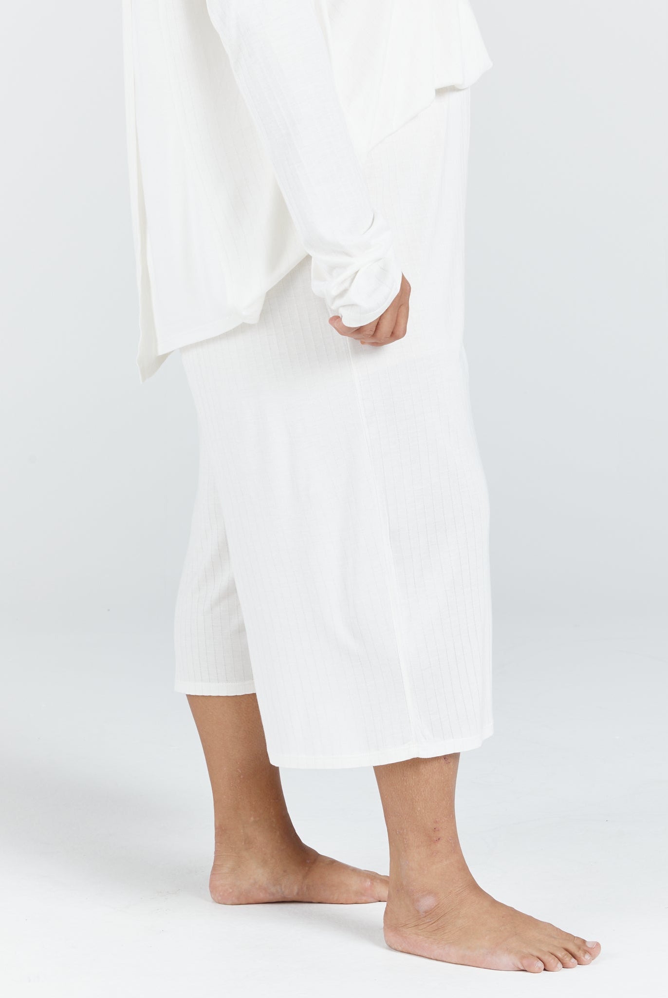 Essensual PJ Pant shown in crisp white, featuring a comfortable cropped length that falls mid-calf. Side view displaying the relaxed fit and lightweight fabric, perfect for comfortable nighttime wear.