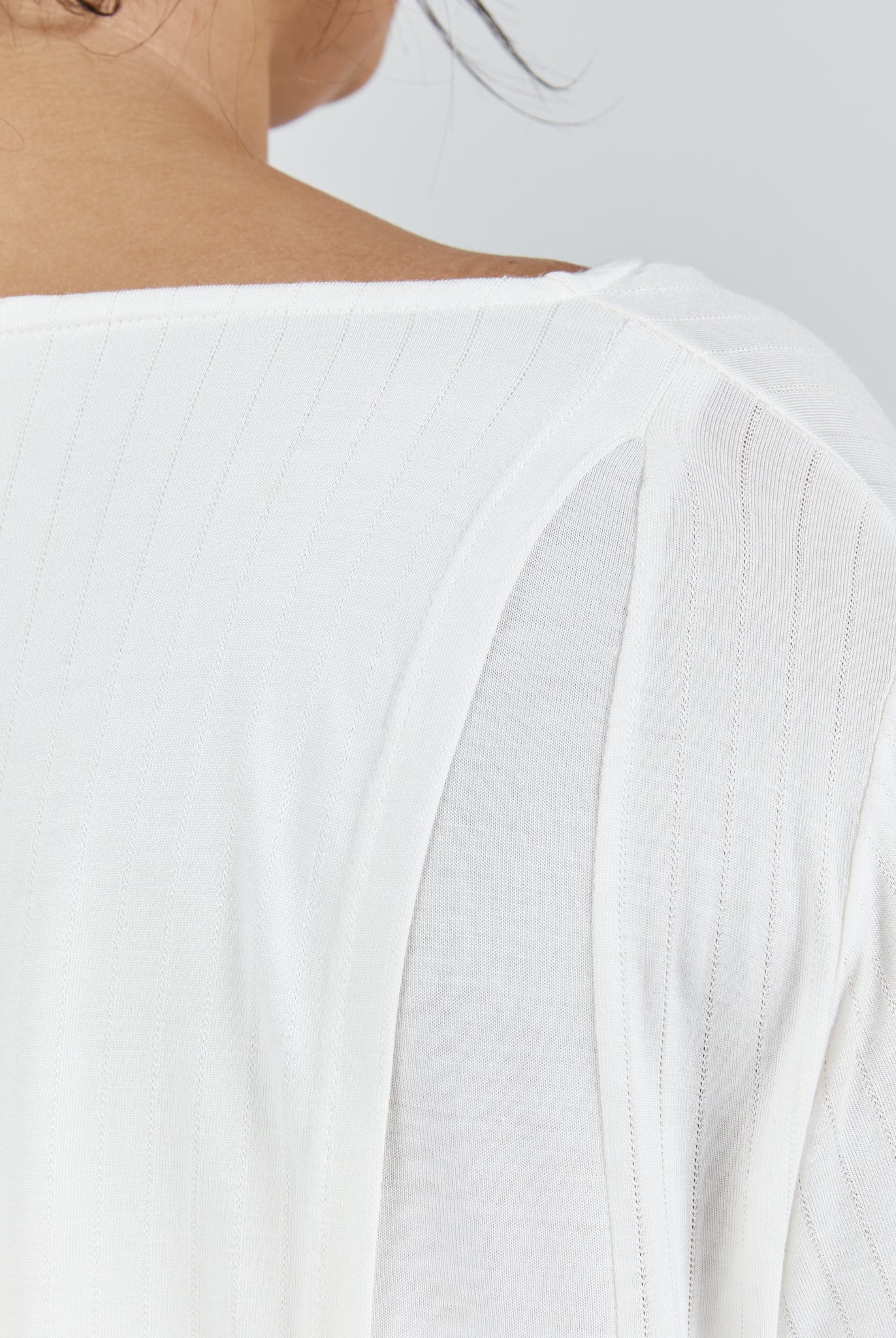 Close-up view of Essensual PJ Top in white, showing delicate ribbed texture and shoulder detail with elegant draping fabric. Features a soft, breathable material with refined stitching visible along the neckline and shoulder seam.