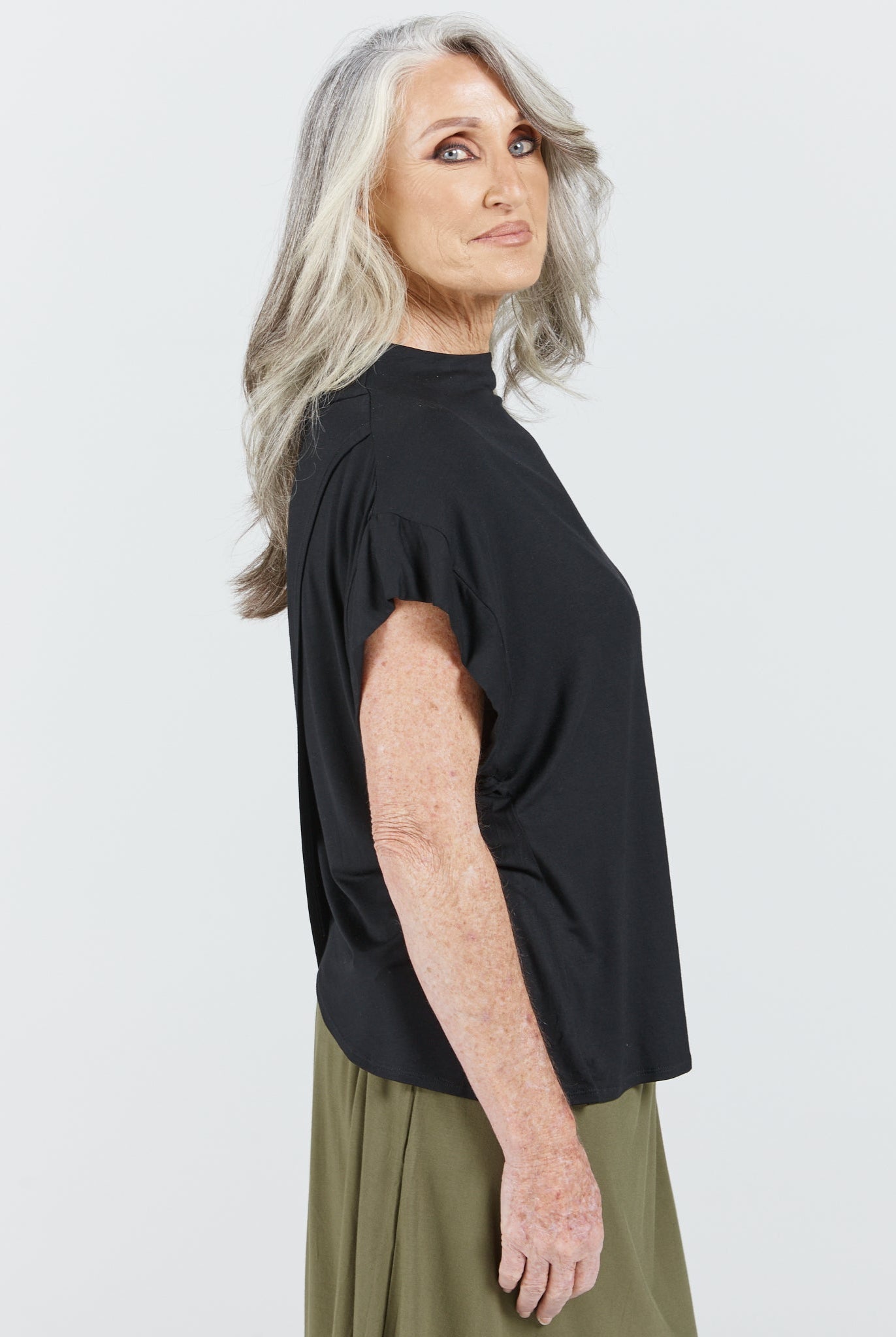 Elegant Leaf Back Blouse in classic black featuring a high neckline and relaxed silhouette, shown in side profile against a white background. The Asian-inspired design showcases clean lines and sophisticated simplicity, perfect for versatile styling.