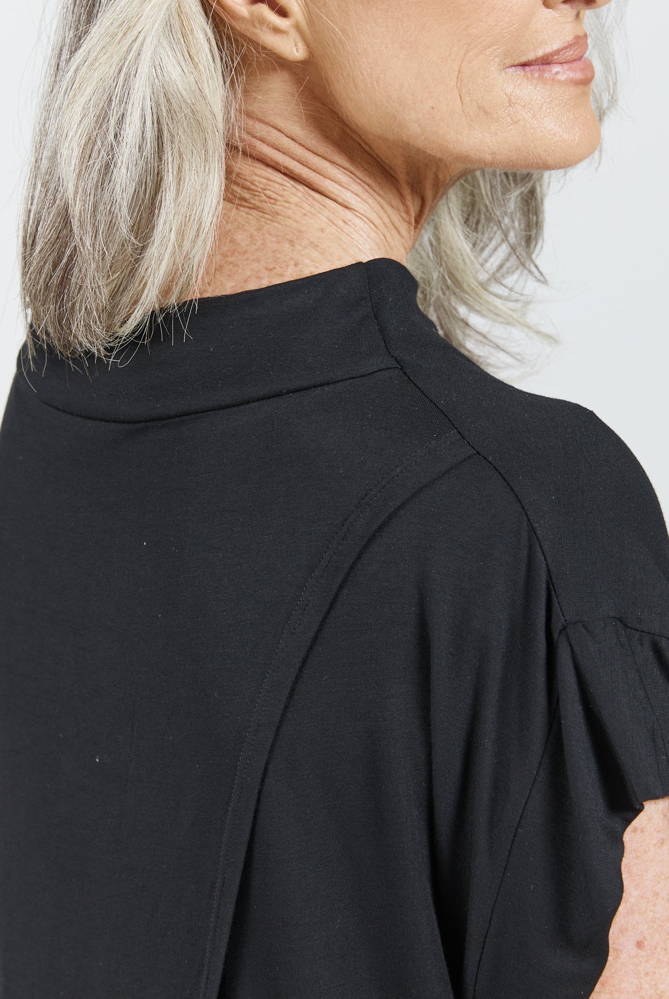 Side profile view of Leaf Back Blouse in classic black, featuring an elegant high neckline and relaxed fit. The minimalist Asian-inspired design is shown against a white background, highlighting the clean lines and sophisticated silhouette.