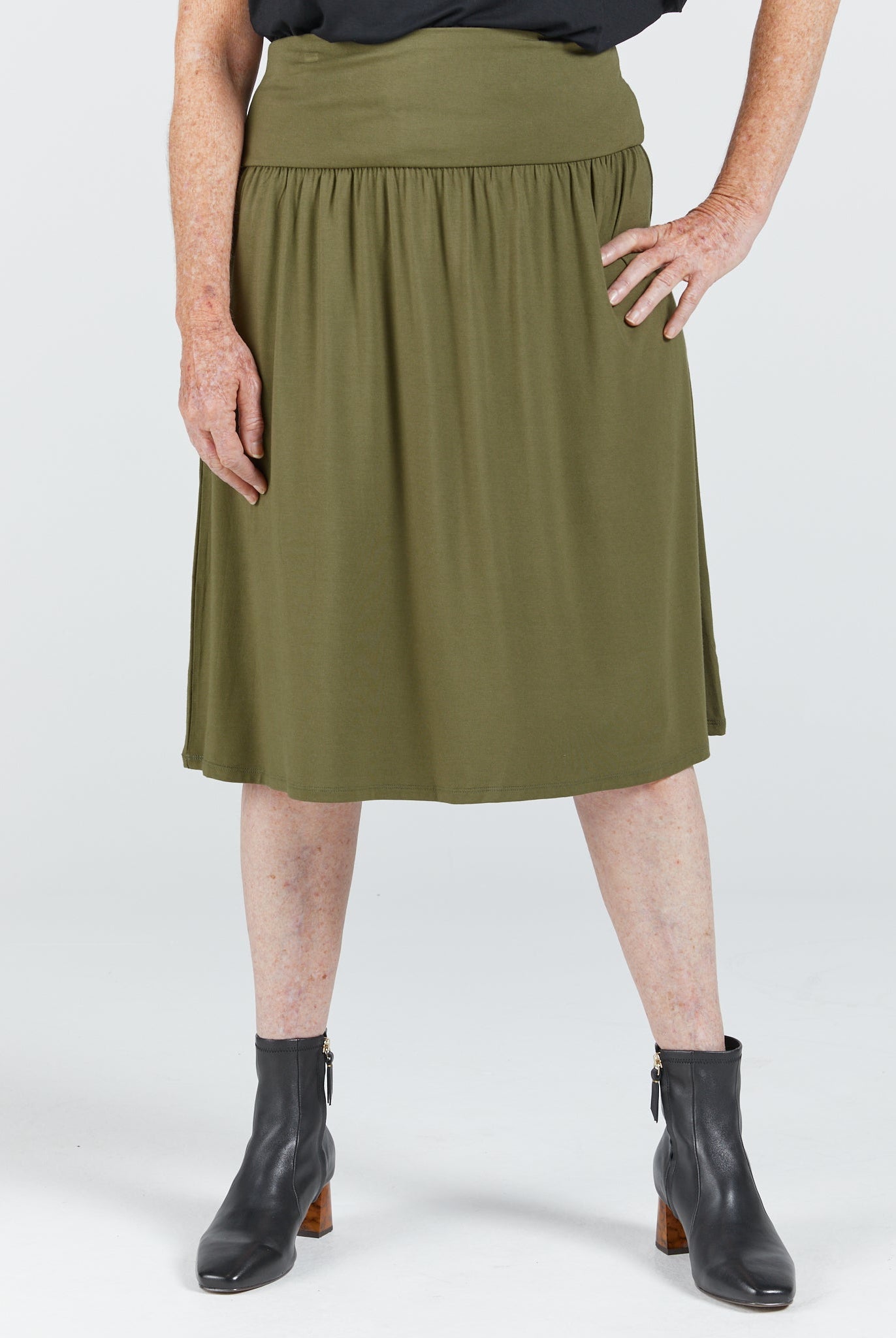 Olive green A-Line skirt with stretchy bamboo fabric features a comfortable wide waistband and side pull tabs for easy dressing. The knee-length adaptive skirt has a flowing silhouette and skips complex fasteners for accessibility.