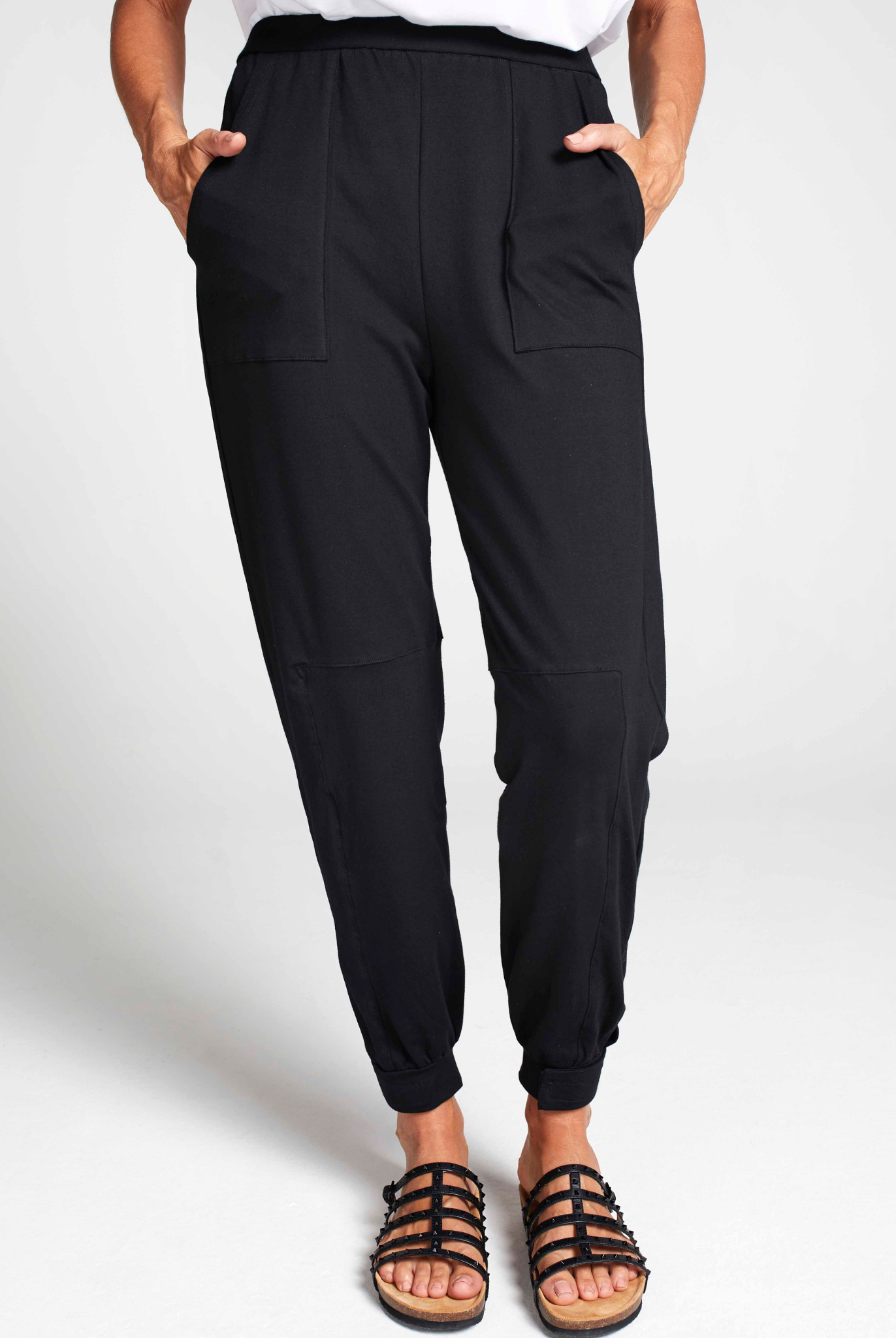 Tapered Track Pants with Hidden Pouch shown in black, featuring elastic ankle cuffs, side pockets, and a relaxed fit silhouette. Styled with sandals and white top against light background, displaying comfortable athletic-casual design perfect for everyday wear.