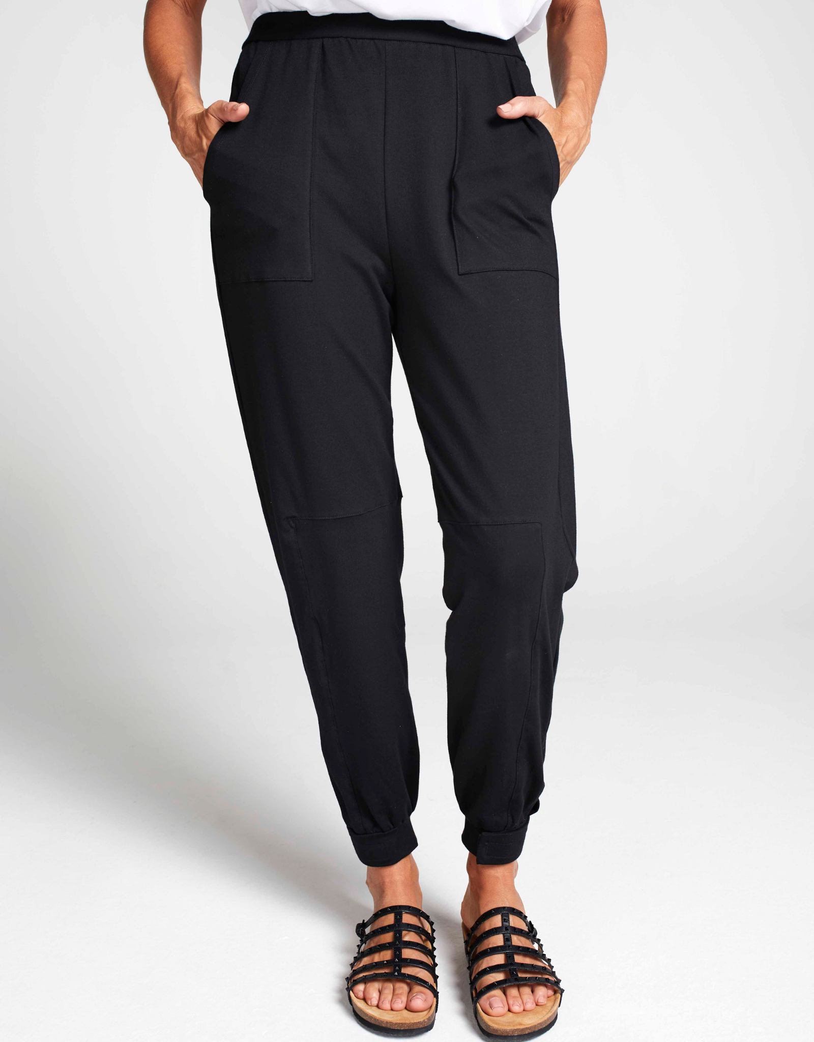 Tapered Track Pants with Hidden Pouch shown in black, featuring elastic ankle cuffs, side pockets, and a relaxed fit silhouette. Styled with sandals and white top against light background, displaying comfortable athletic-casual design perfect for everyday wear.