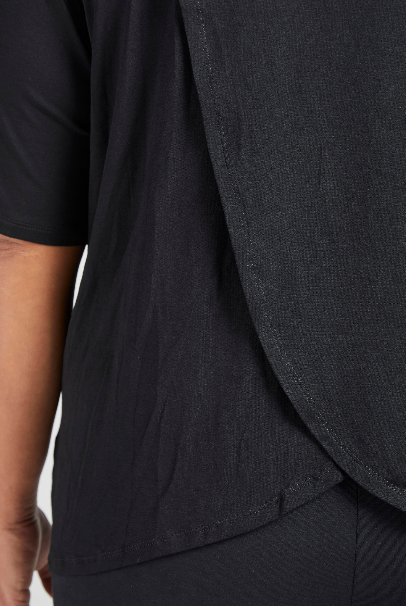 Short Sleeve Leaf Back T-Shirt featuring a stylish black design with curved hem detail and elegant draping at the back, showcasing a modern silhouette and premium fabric quality