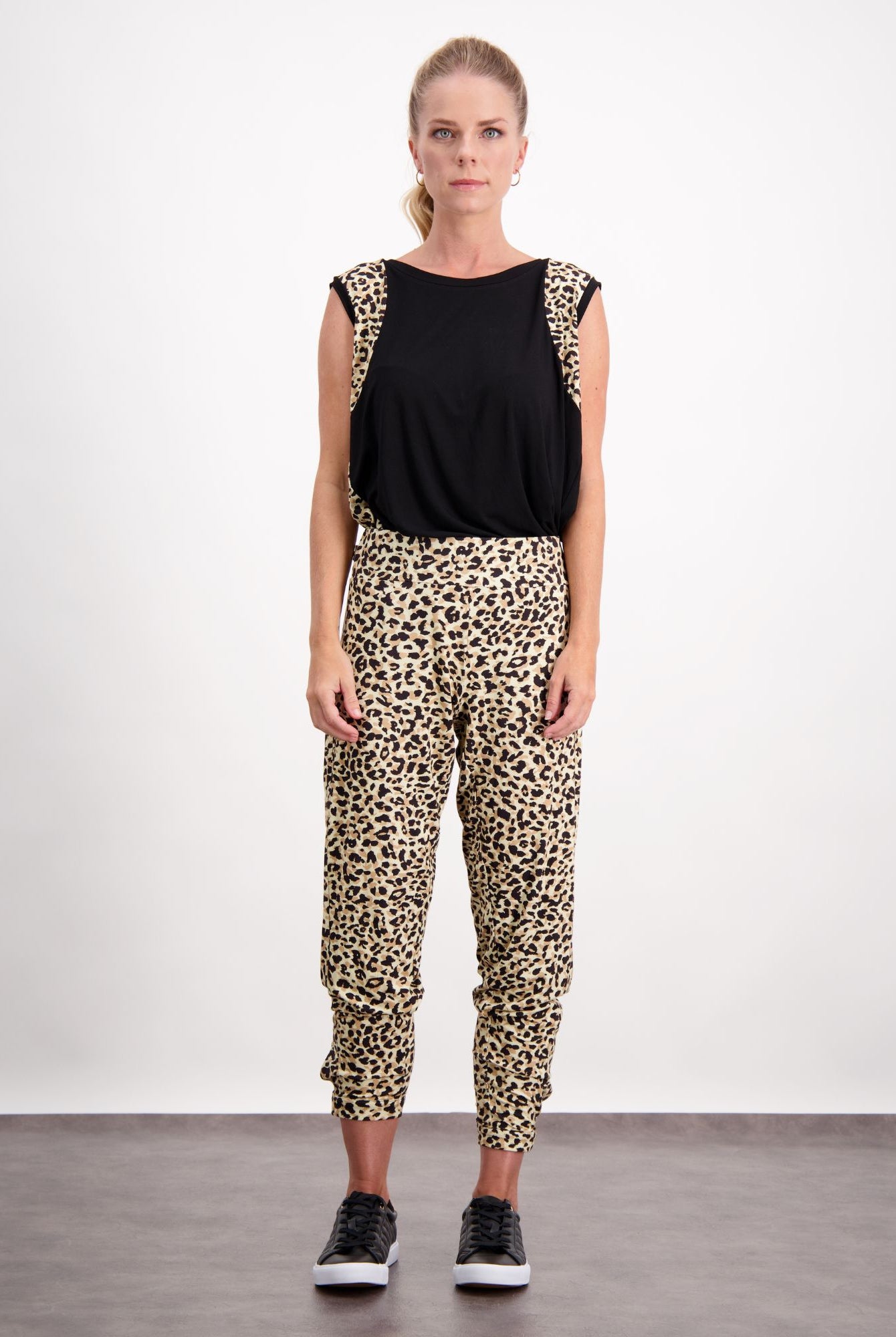 Natasha Physio Leggings shown in leopard print pattern with black sleeveless top, styled for adaptive wear. Model wearing black sneakers against white background, demonstrating comfortable fit and versatile styling options for casual to athletic wear.