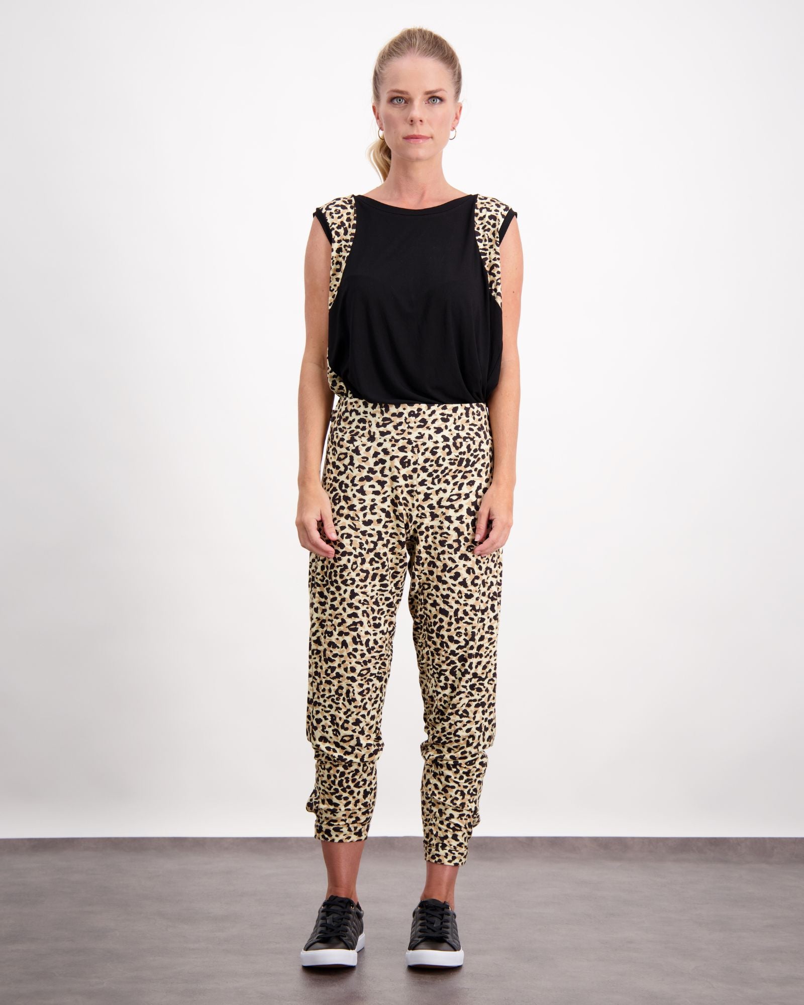 Natasha Physio Leggings shown in leopard print pattern with black sleeveless top, styled for adaptive wear. Model wearing black sneakers against white background, demonstrating comfortable fit and versatile styling options for casual to athletic wear.