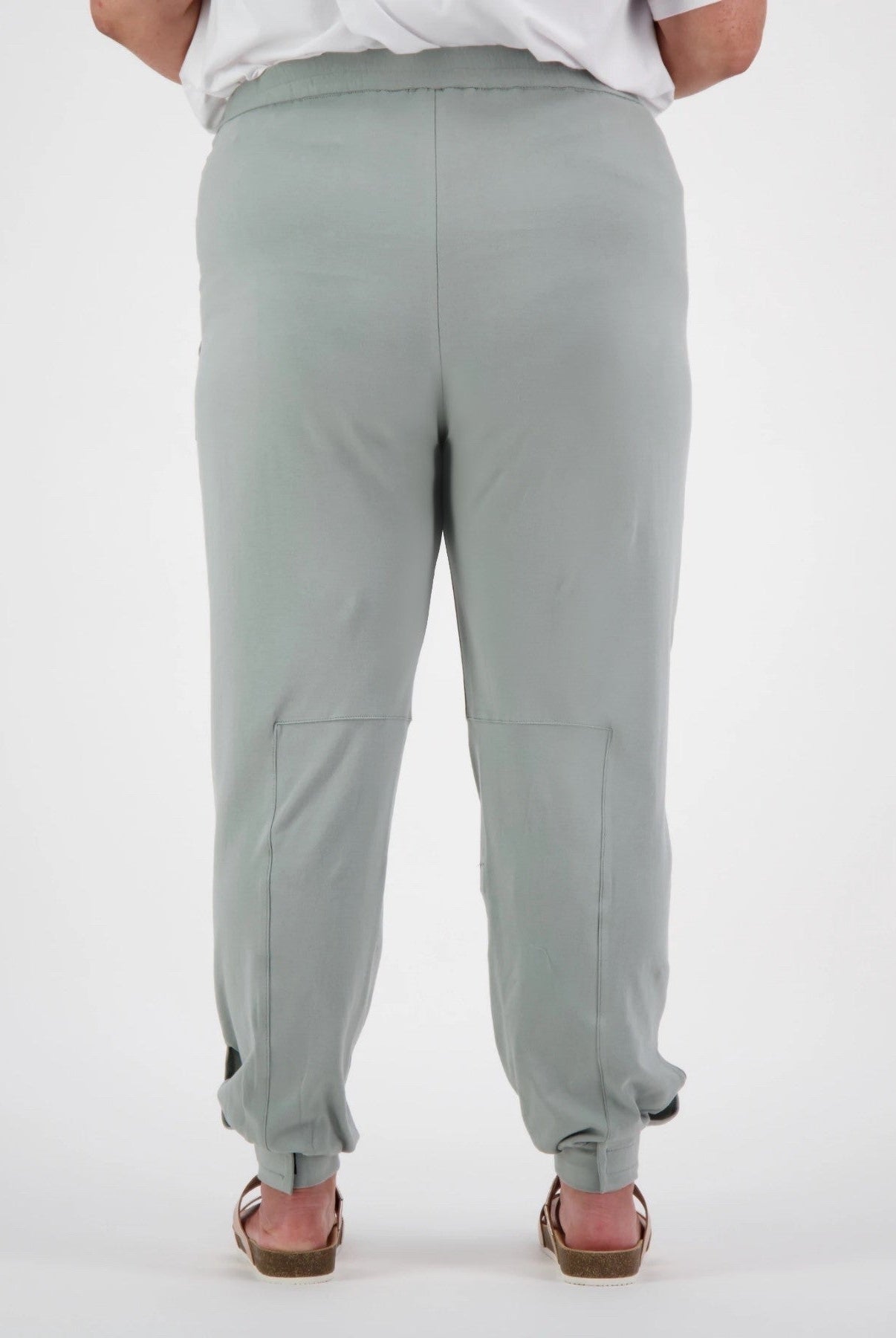 Tapered Track Pants with Hidden Pouch shown from back view in soft sage green color, featuring tapered legs, elastic cuffs, and concealed inner pouch design. Paired with white top to showcase relaxed, comfortable fit and practical medical-wear styling.