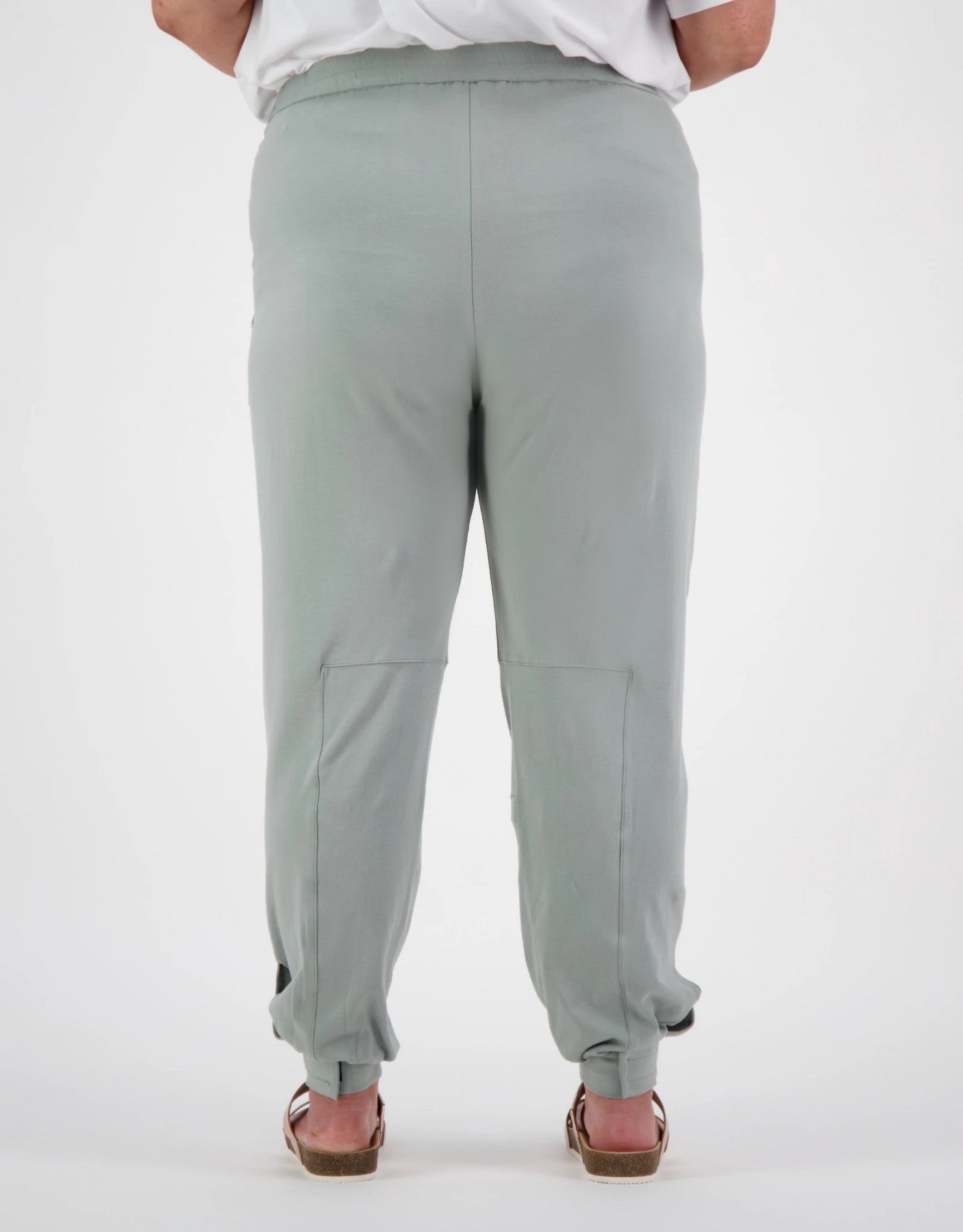 Tapered Track Pants with Hidden Pouch shown from back view in soft sage green color, featuring tapered legs, elastic cuffs, and concealed inner pouch design. Paired with white top to showcase relaxed, comfortable fit and practical medical-wear styling.