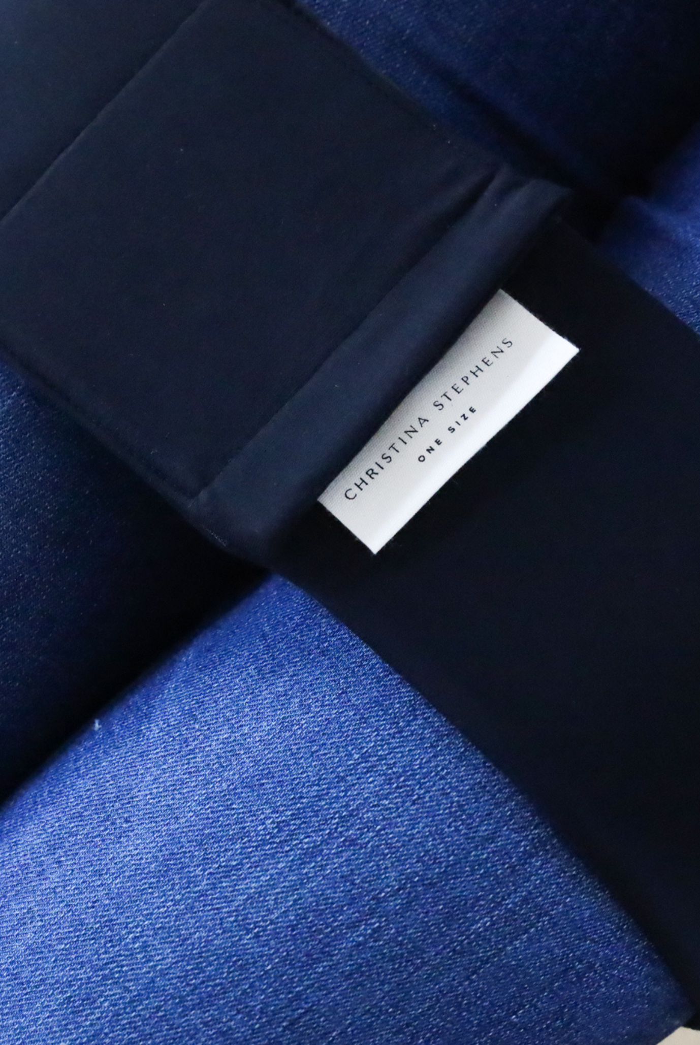 Wheelchair Leg Strap shown in black and denim blue colors with branded label, displaying contrast between smooth black fabric and textured denim material, designed for comfortable wheelchair seating position.