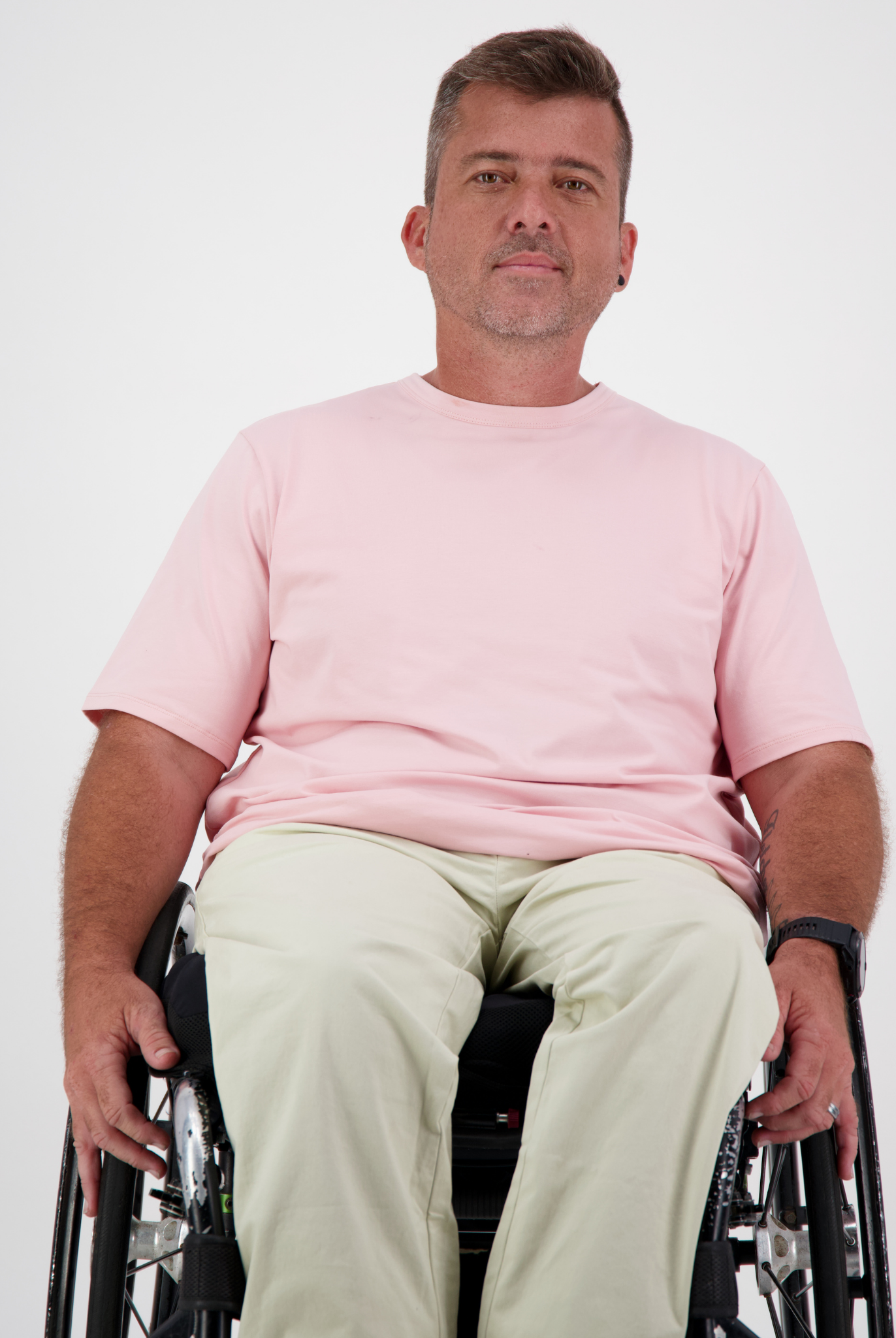 Short Sleeve Prism Back T-Shirt shown in soft pink color worn with beige pants, photographed against white background featuring adaptive clothing design for wheelchair users, demonstrating comfort and accessibility in casual wear