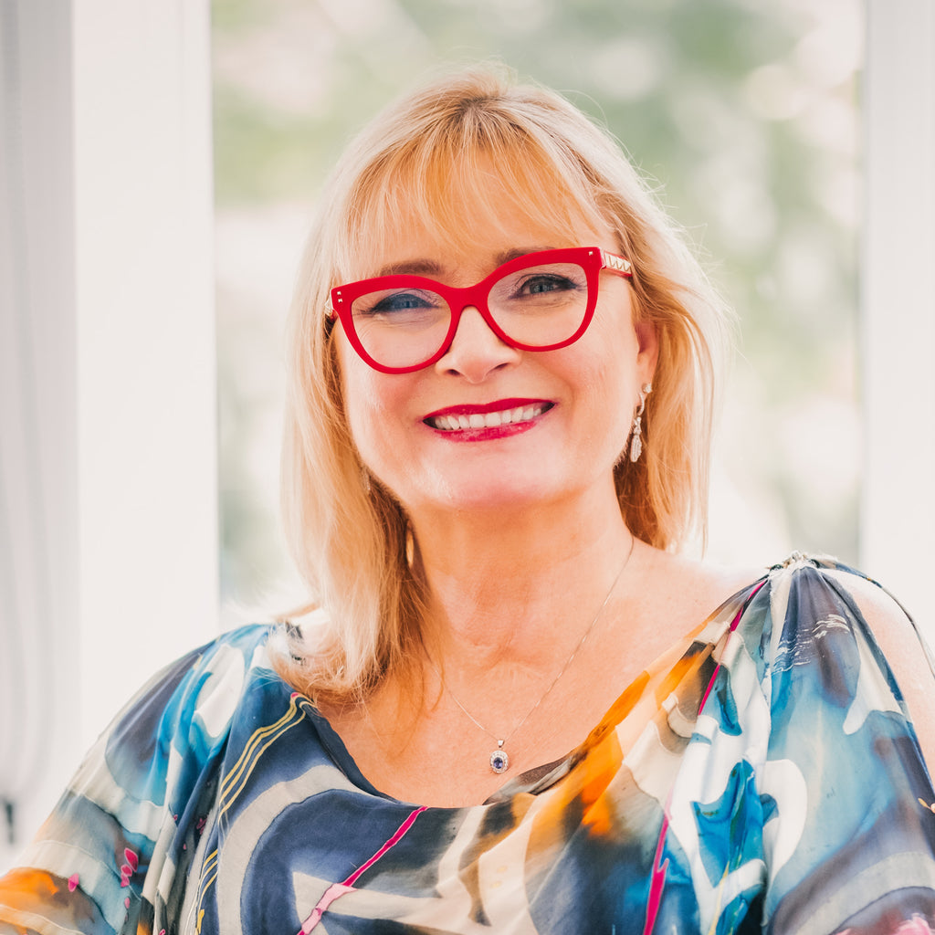 Image of a female (Carol) wearing a patterned green top and red glasses. She is smiling. Christina Stephens Adaptive Clothing Australia.