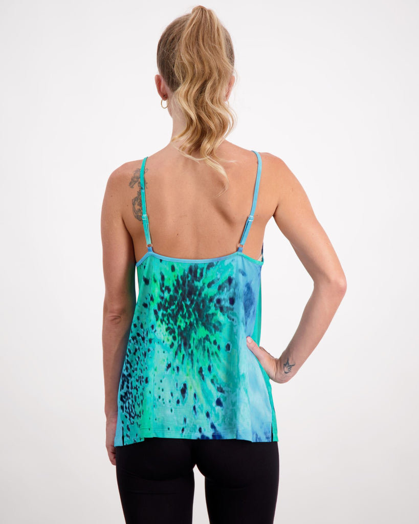 Blonde standing female is wearing a aqua blue (oceania print) camisole top with gold loop earrings. She is facing to the back. Christina Stephens Australian Adaptive Clothing.