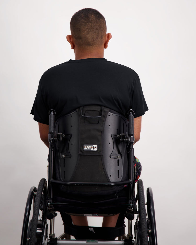 Male in a wheelchair wearing a black t-shirt and colourful boardshorts. Christina Stephens Adaptive Clothing Australia. 