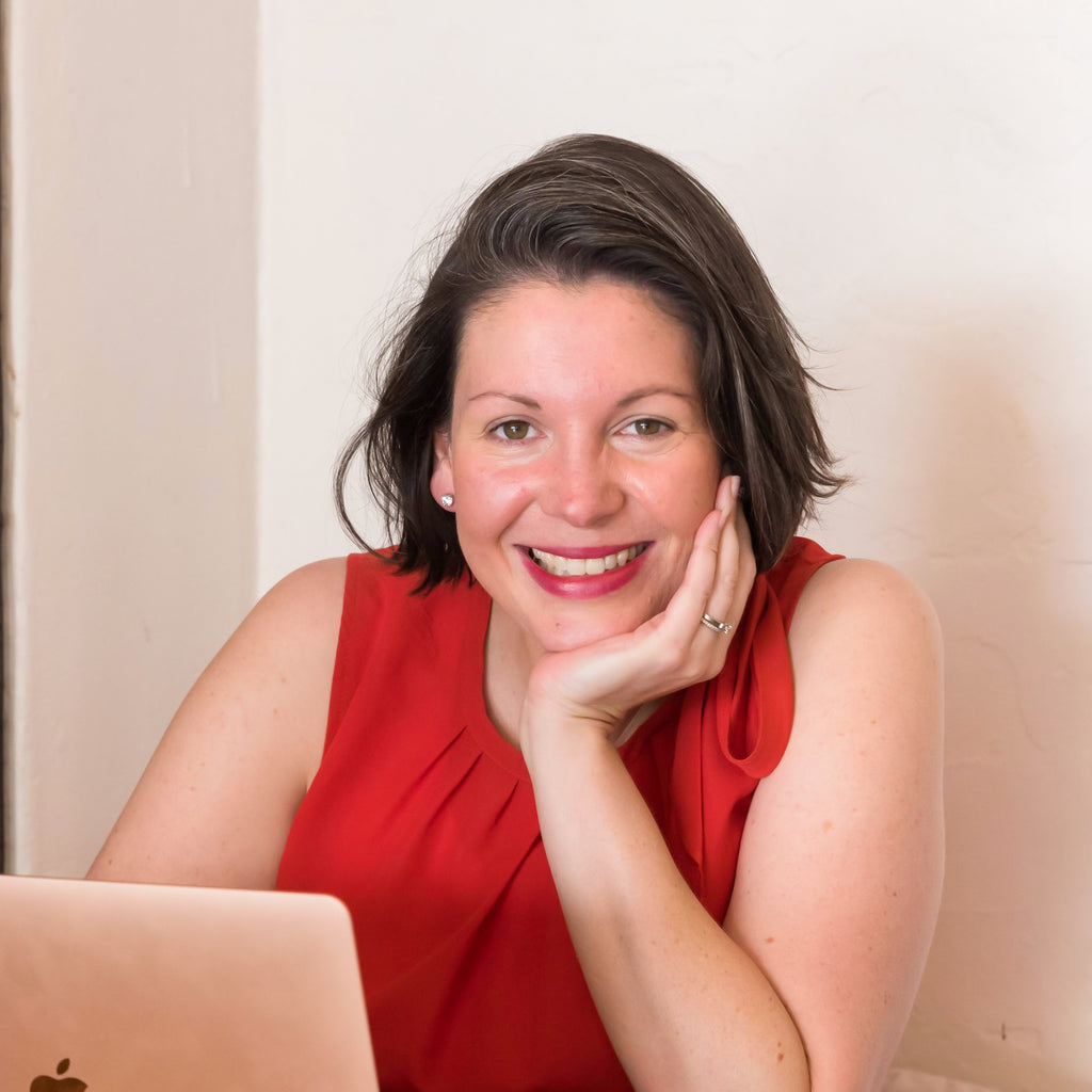 Image of a female (Clare) with brunette hair, wearing a red top is sitting with her hand under her chin in front of a laptop. Christina Stephens Adaptive Clothing Australia.