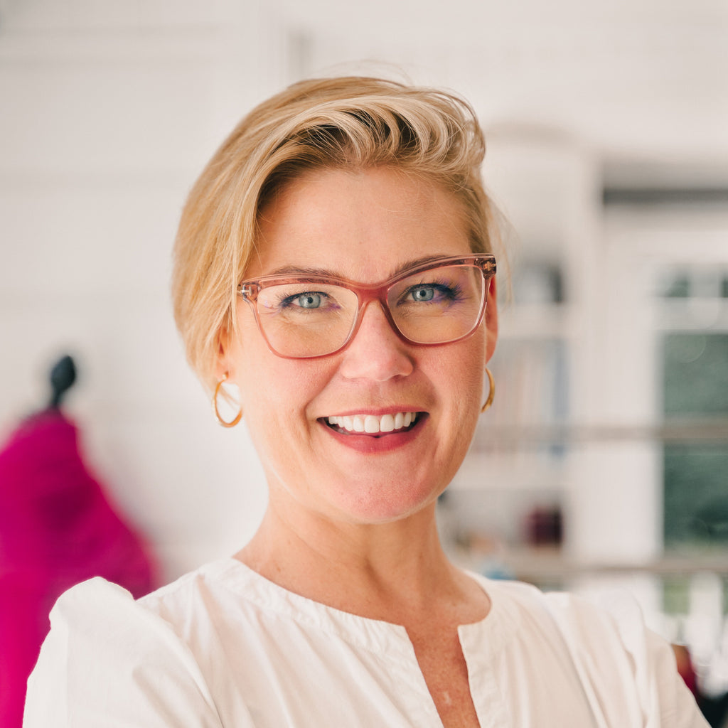 Image of a female (Jessie) wearing a white shirt and pink glasses. She is smiling. Christina Stephens Adaptive Clothing Australia.