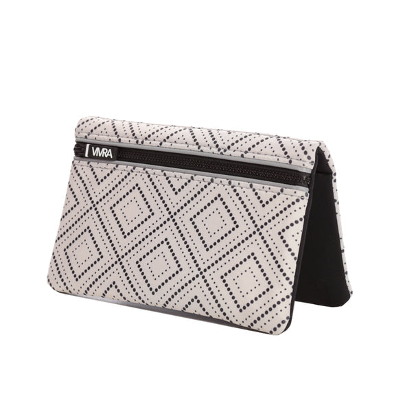 The VIVRA ‘Vivid’ waist bag in a black and white geometric pattern reminiscent of the Art Deco style, with a black zipper and a brand tag that says, ‘Vivra’, standing upright against a white background.