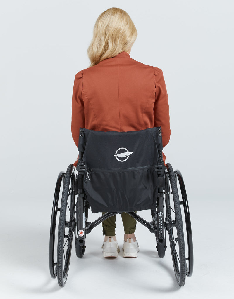 Image of a blonde female in a wheelchair wearing a brick red jacket. She is facing backwards. Christina Stephens Adaptive Clothing Australia. 