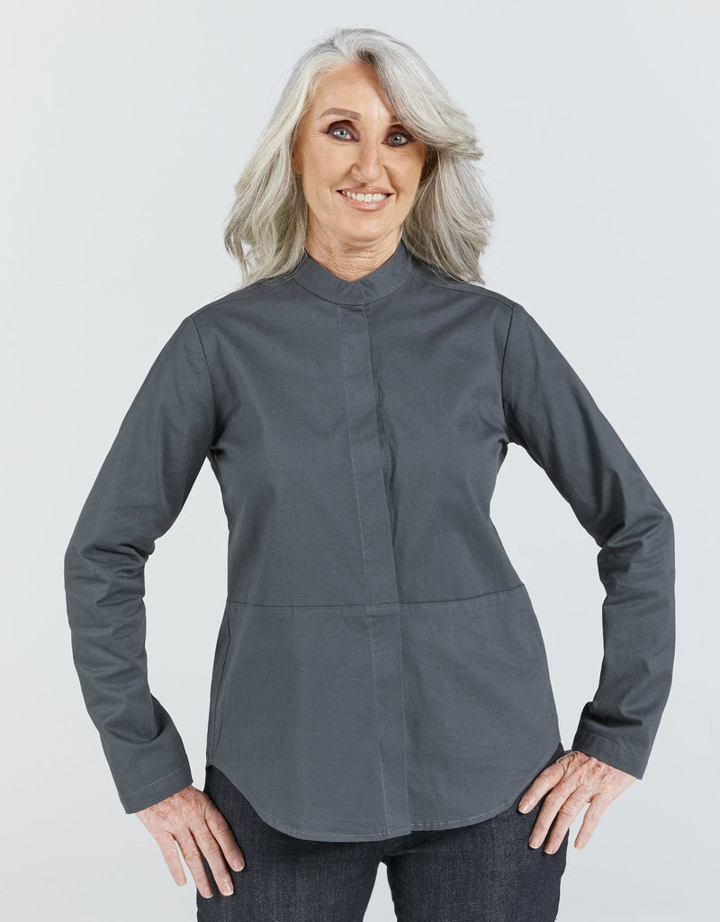 Image of a grey haired, standing female wearing a dark grey Chinese collared shirt with dark blue jeans. Christina Stephens Adaptive Clothing Australia. 