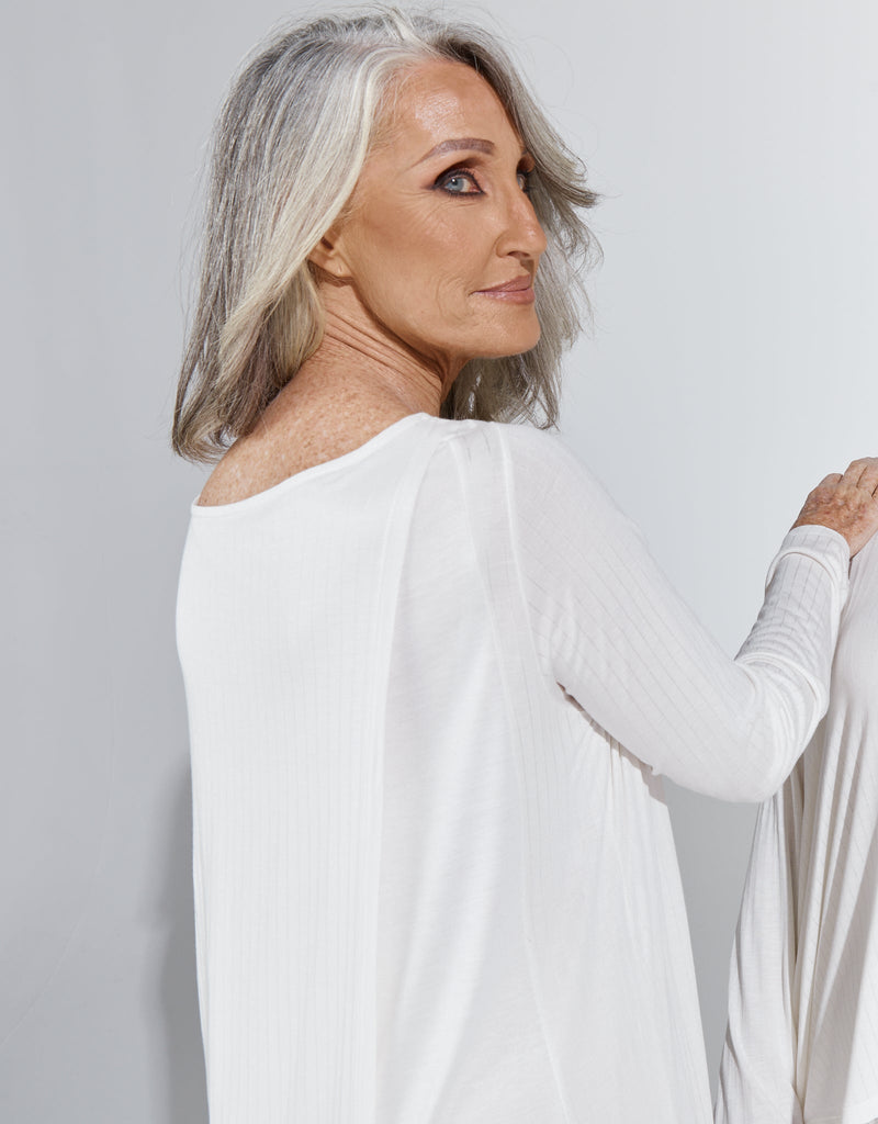Image of a standing female with grey hair wearing a cream knee length, long sleeved night gown. Christina Stephens Adaptive Clothing Australia. 