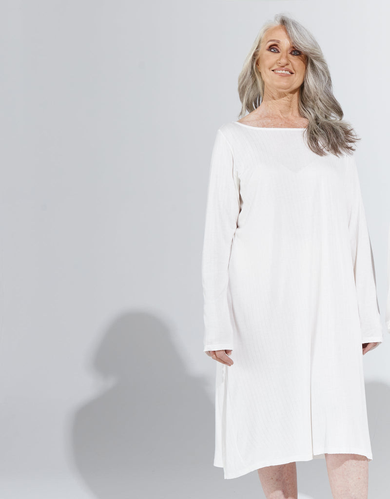 Image of a standing female with grey hair wearing a cream knee length, long sleeved night gown. Christina Stephens Adaptive Clothing Australia. 