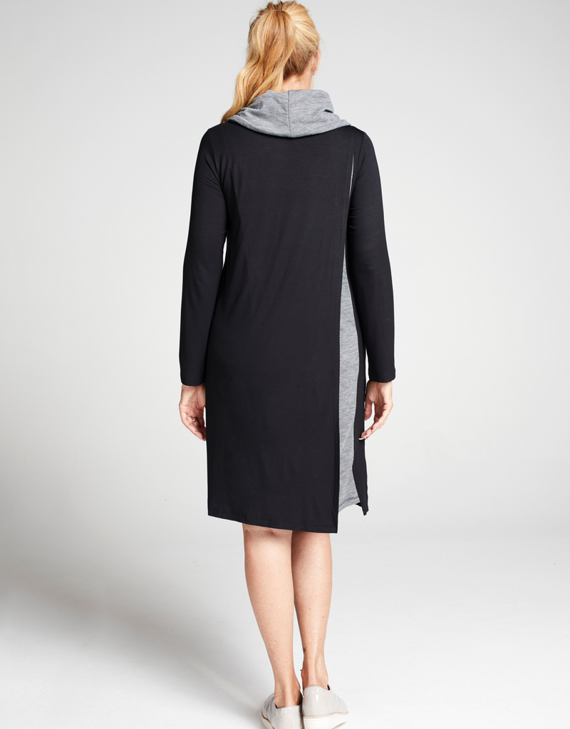 Blonde woman wearing a knee length, black long sleeve dress with grey stripe cowl neck. Standing back facing.