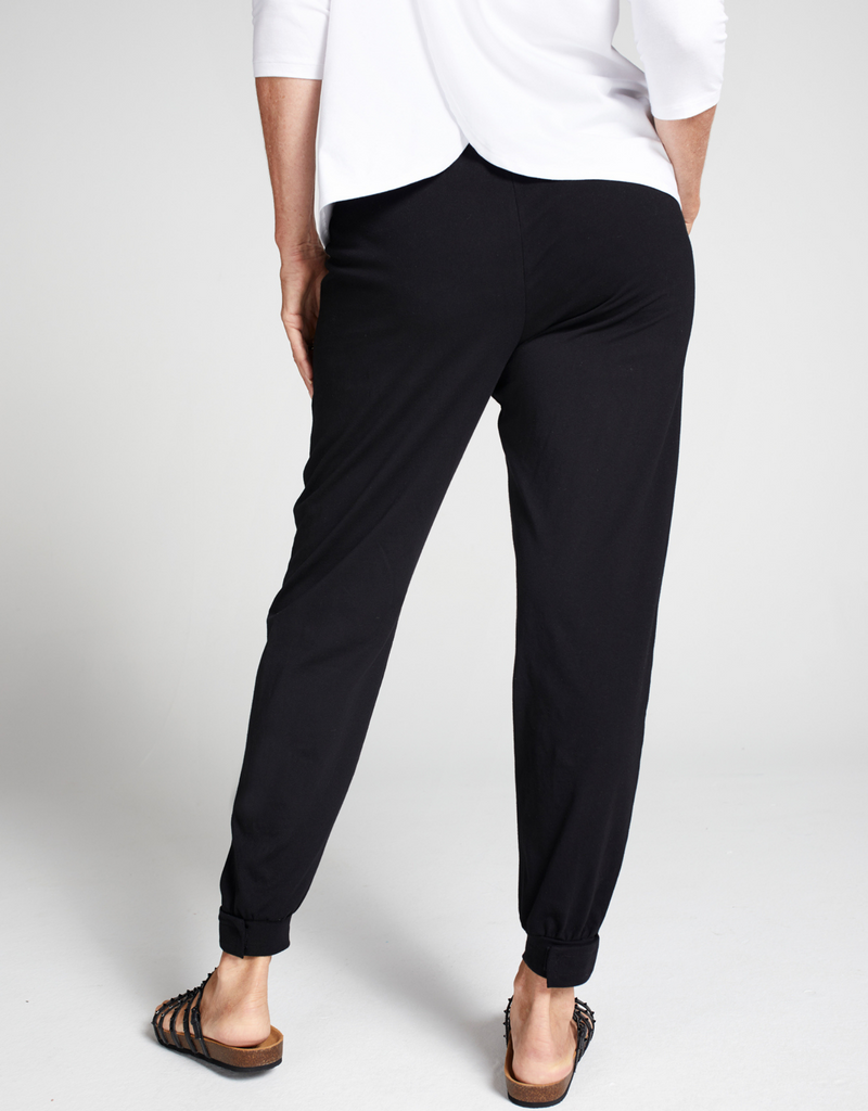Woman wearing black tapered leg pants with square pocket detail, cuff at leg opening and black sandals. Backward facing. Back view of garment. 