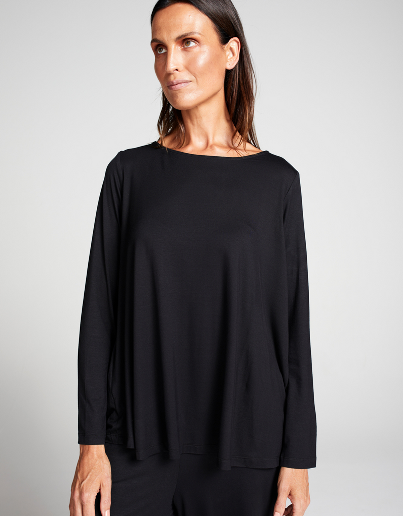 Brunette woman wearing a loose fitting black top with round neck line and long sleeves. Standing. Forward facing.