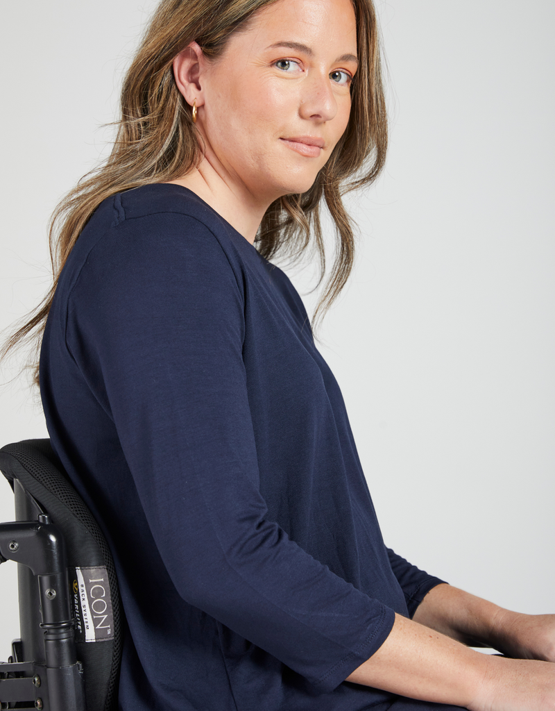 Woman in a wheelchair wearing 3/4 sleeve t-shirt. Side facing.