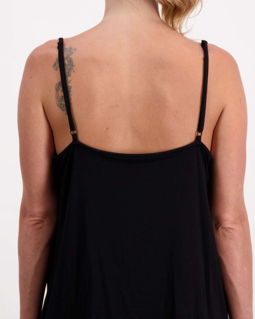 Blonde standing female is wearing a black camisole top with gold loop earrings. She is facing backwards. Close up image showing adjustable straps. Christina Stephens Australian Adaptive Clothing.