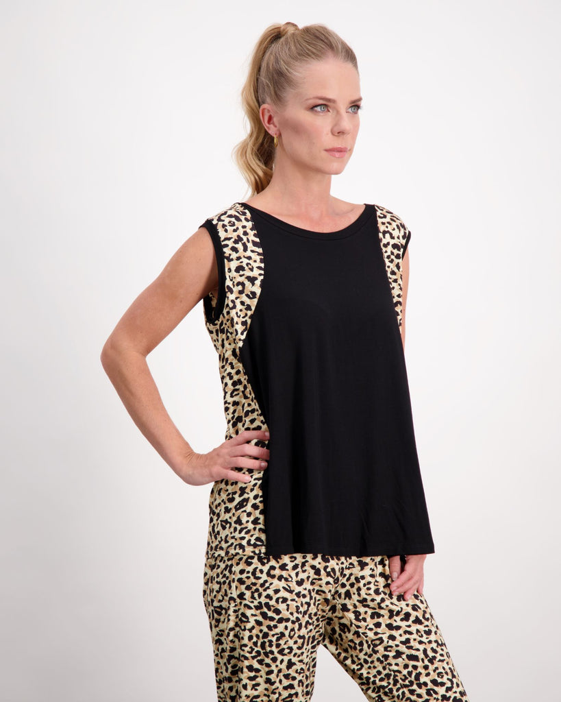 ﻿A standing blonde female with blue eyes wearing a pony-tail is wearing a black and leopard print bamboo sleeveless physio top. The leopard print highlights the black front of the top. She has paired the top with matching leopard print bamboo pants. Christina Stephens Australian Adaptive Clothing. 