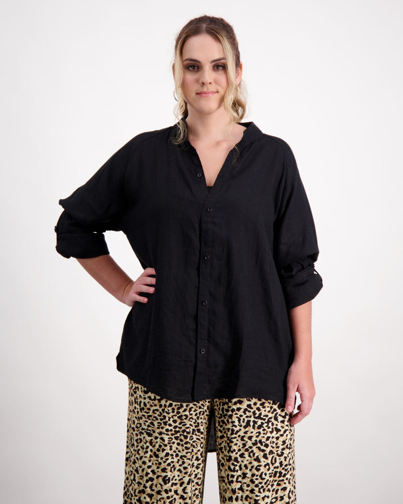 A standing female with caucasian skin and blonde curly hair is wearing a black linen shirt with leopard print wide leg pants. Christina Stephens Australian Adaptive Clothing. 